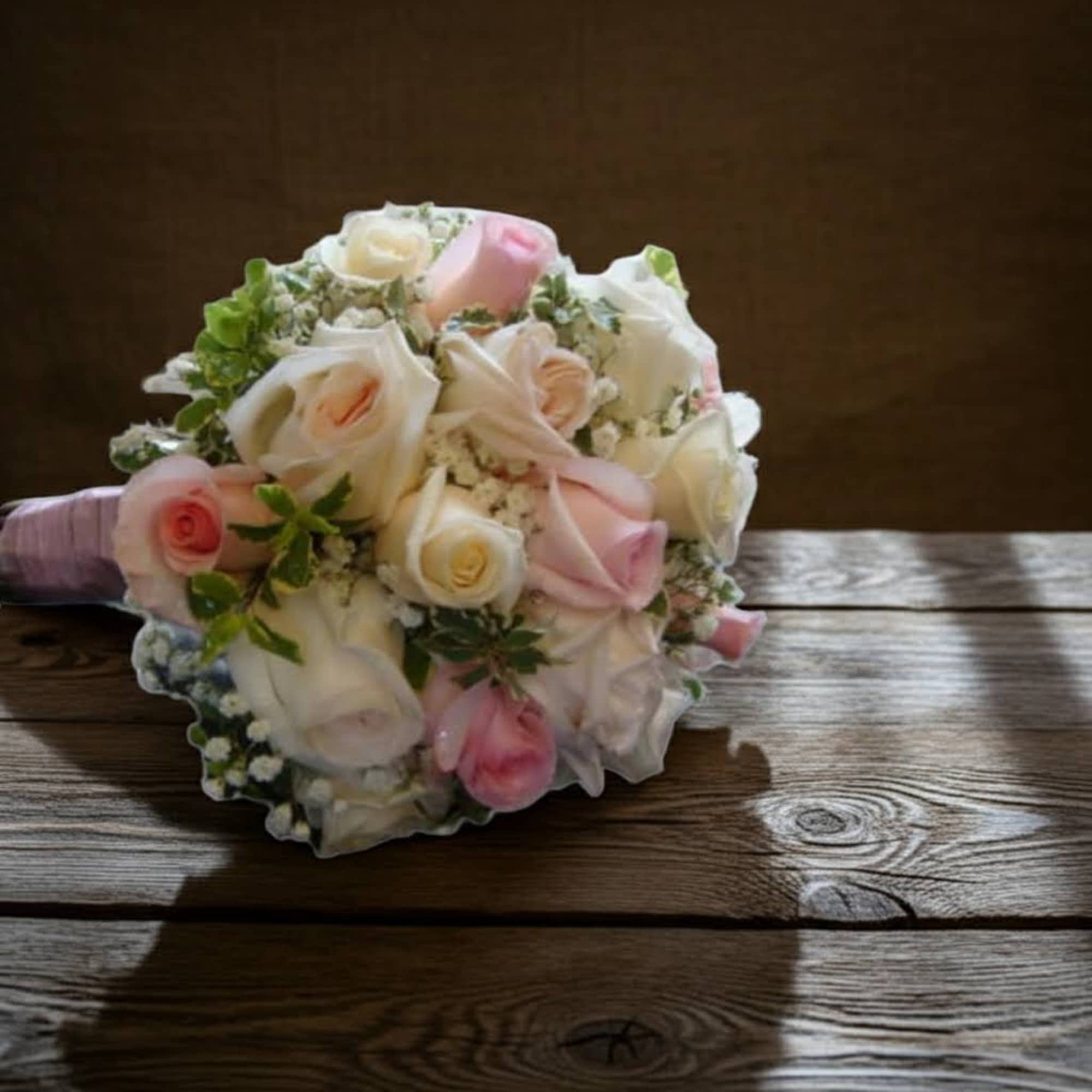 Bouquet of pale pink and white roses on a wooden table