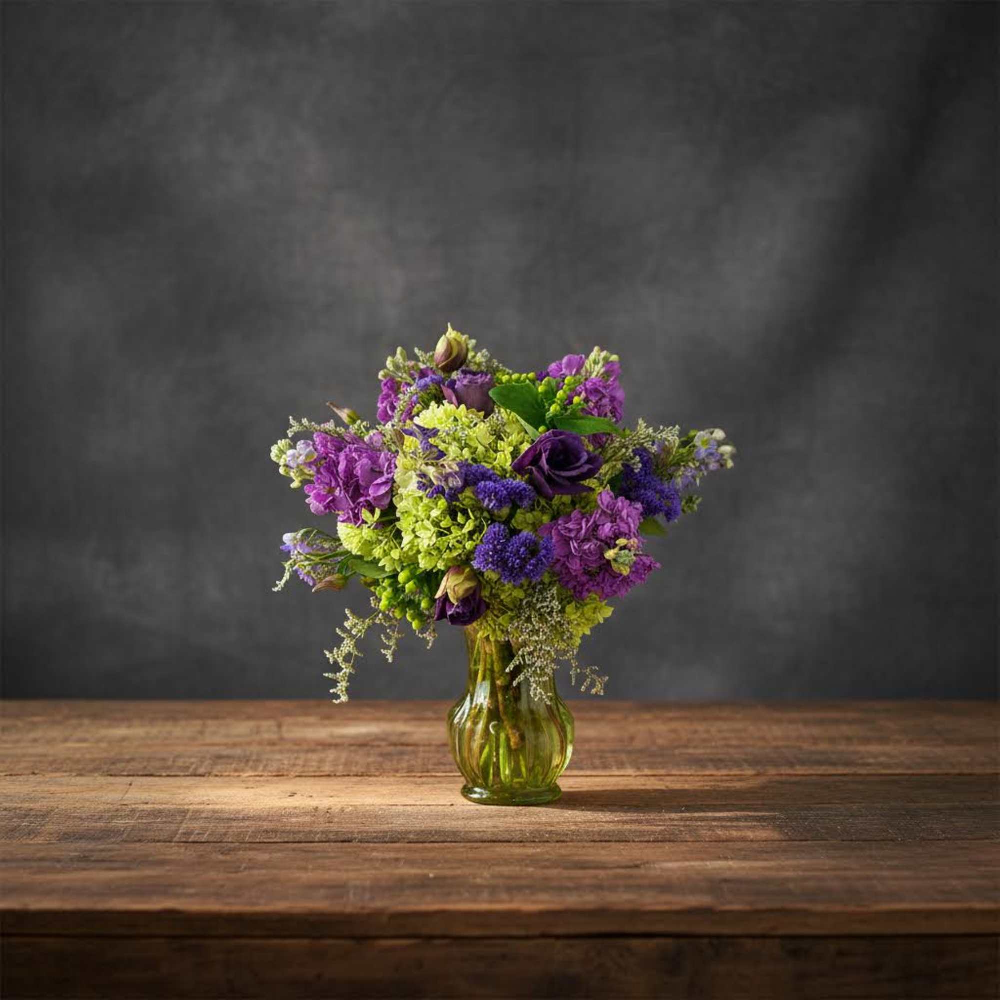Purple and green flower arrangement in a glass vase