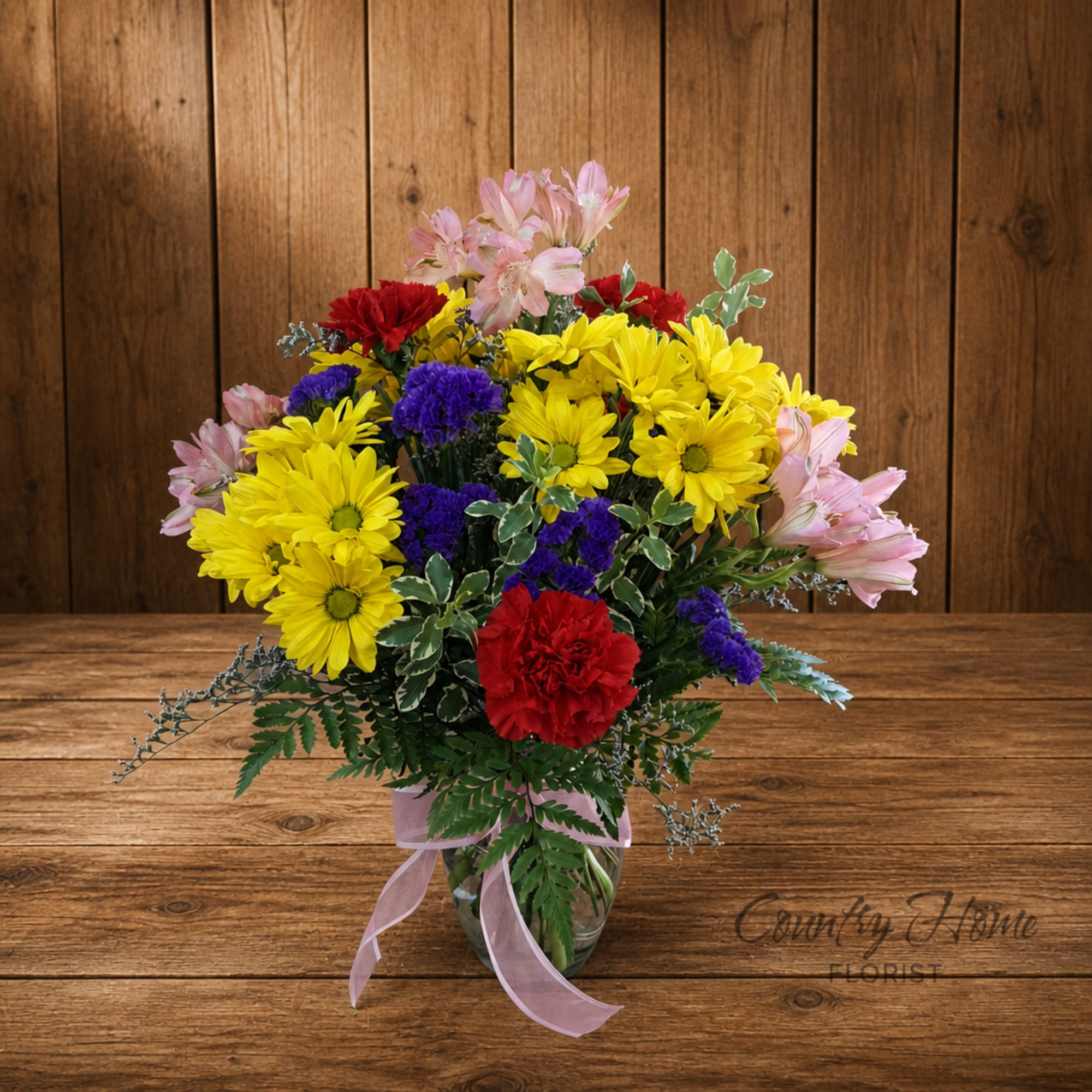 Colorful bouquet of daisies, carnations, and alstroemeria in a glass vase