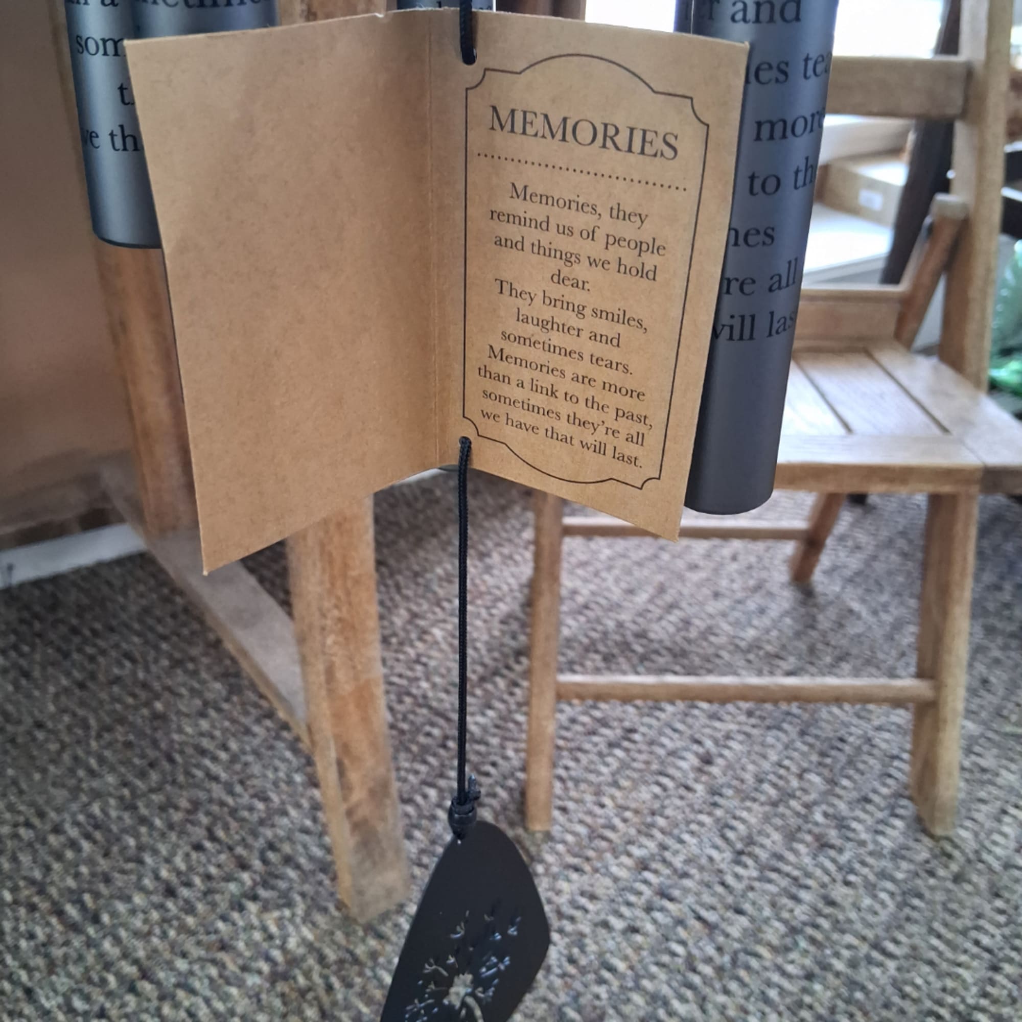 Paper memorial tag hanging from a wooden chair with a black cord