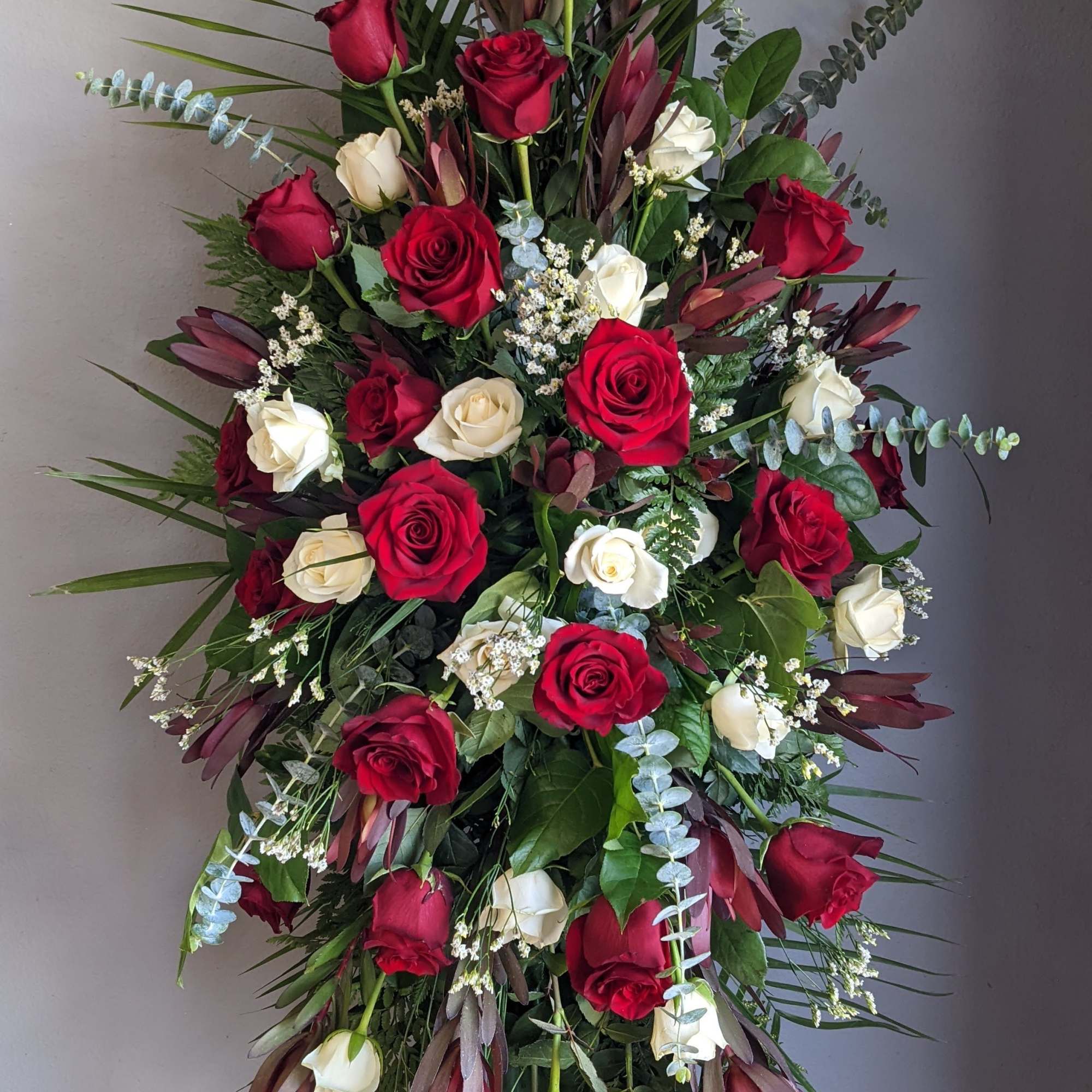 Tall standing spray of red and white roses with greenery
