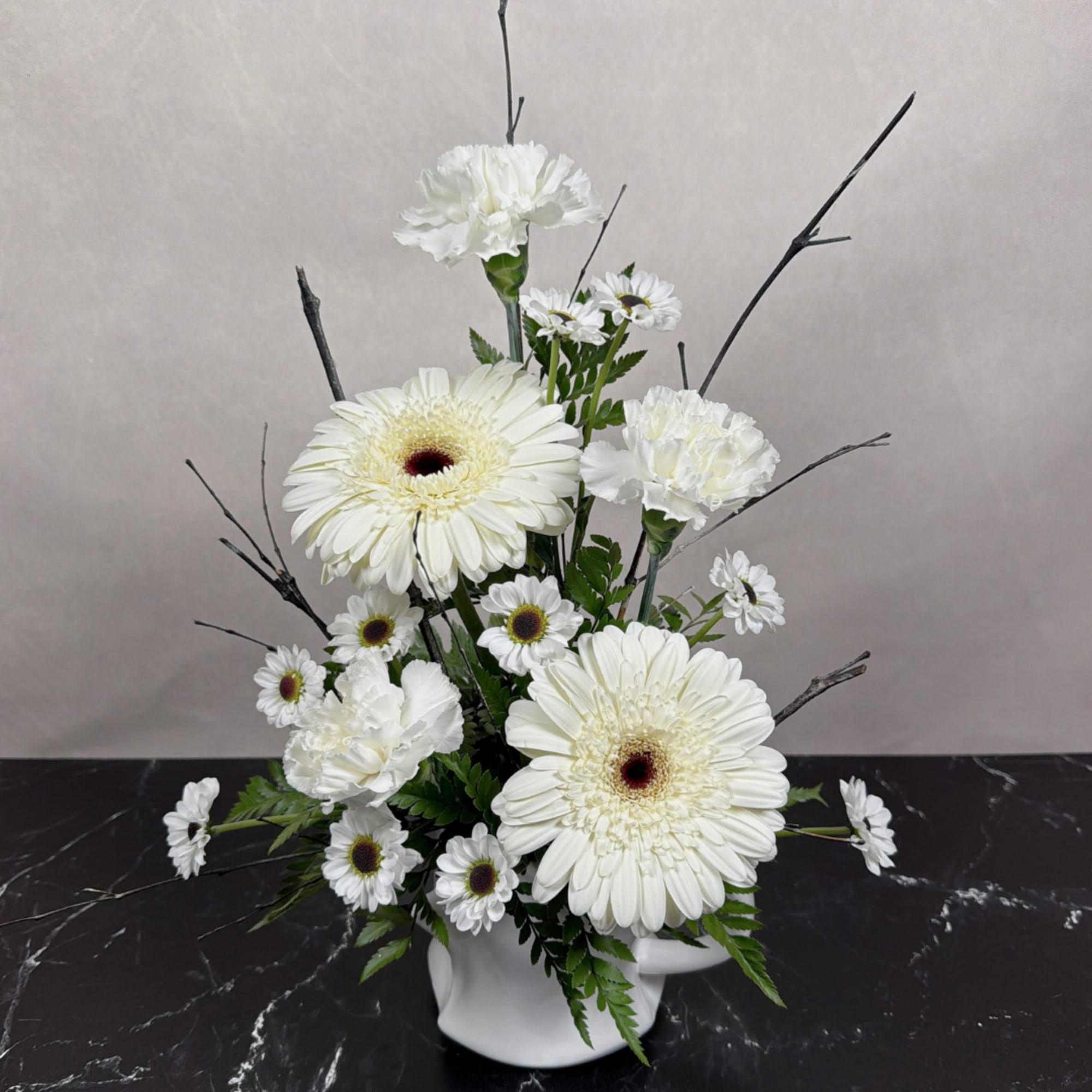 White gerberas and carnations arranged in a white vase