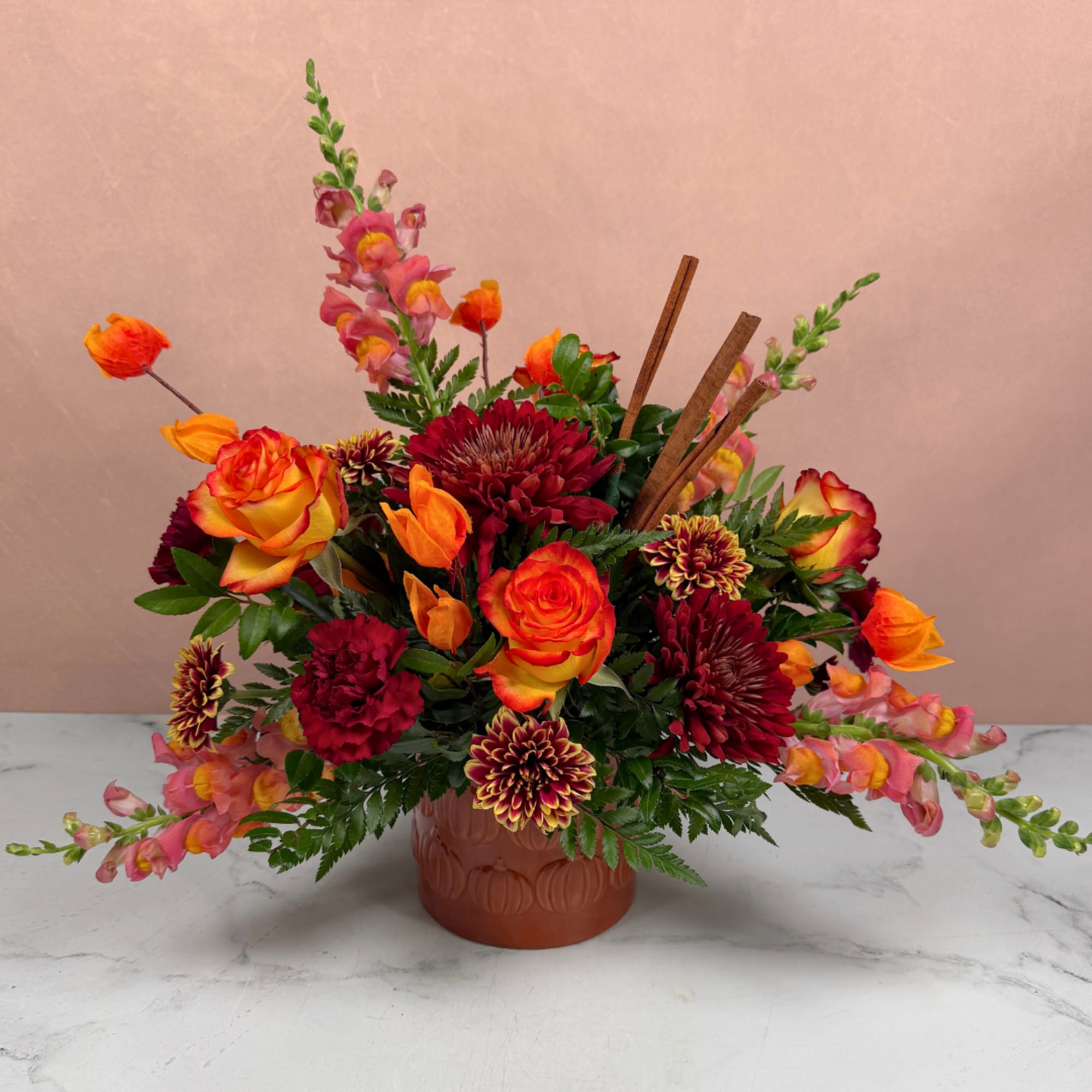 Colorful floral arrangement in a terracotta vase with orange and red blooms