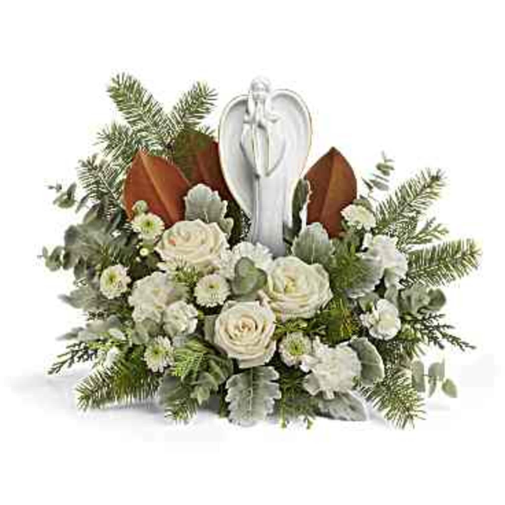 White roses arranged around an angel figurine with evergreen accents