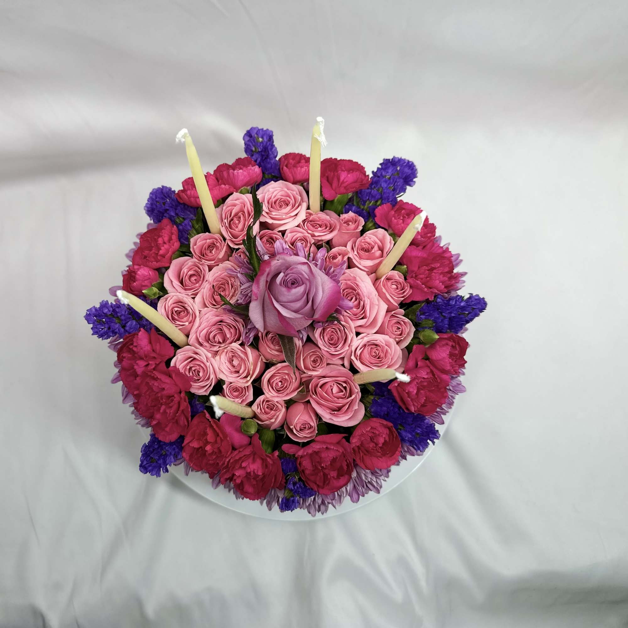 Round bouquet of pink and purple flowers with candles