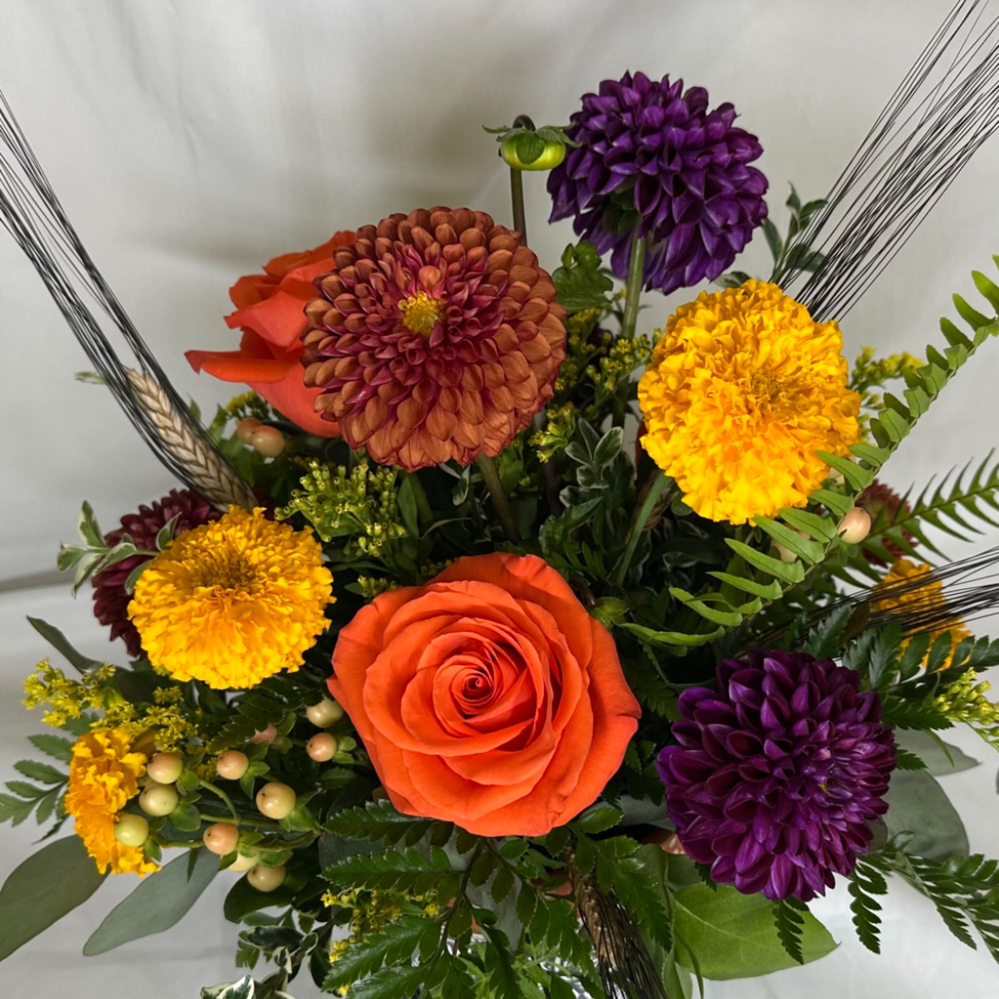 Bouquet of orange roses, purple dahlias, and yellow marigolds