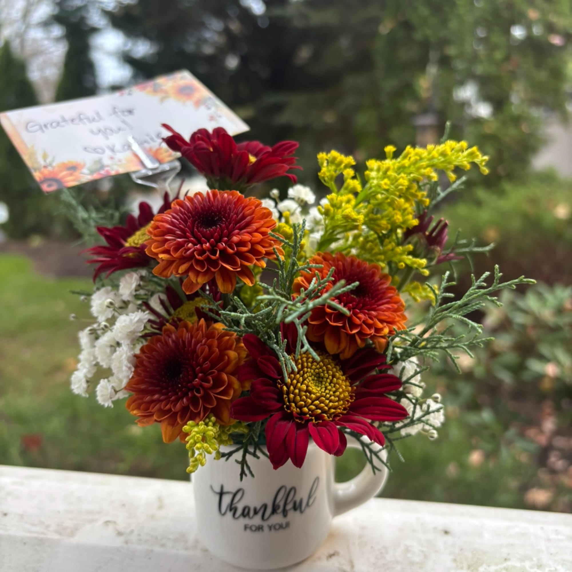Bouquet of red and orange chrysanthemums in a white mug vase