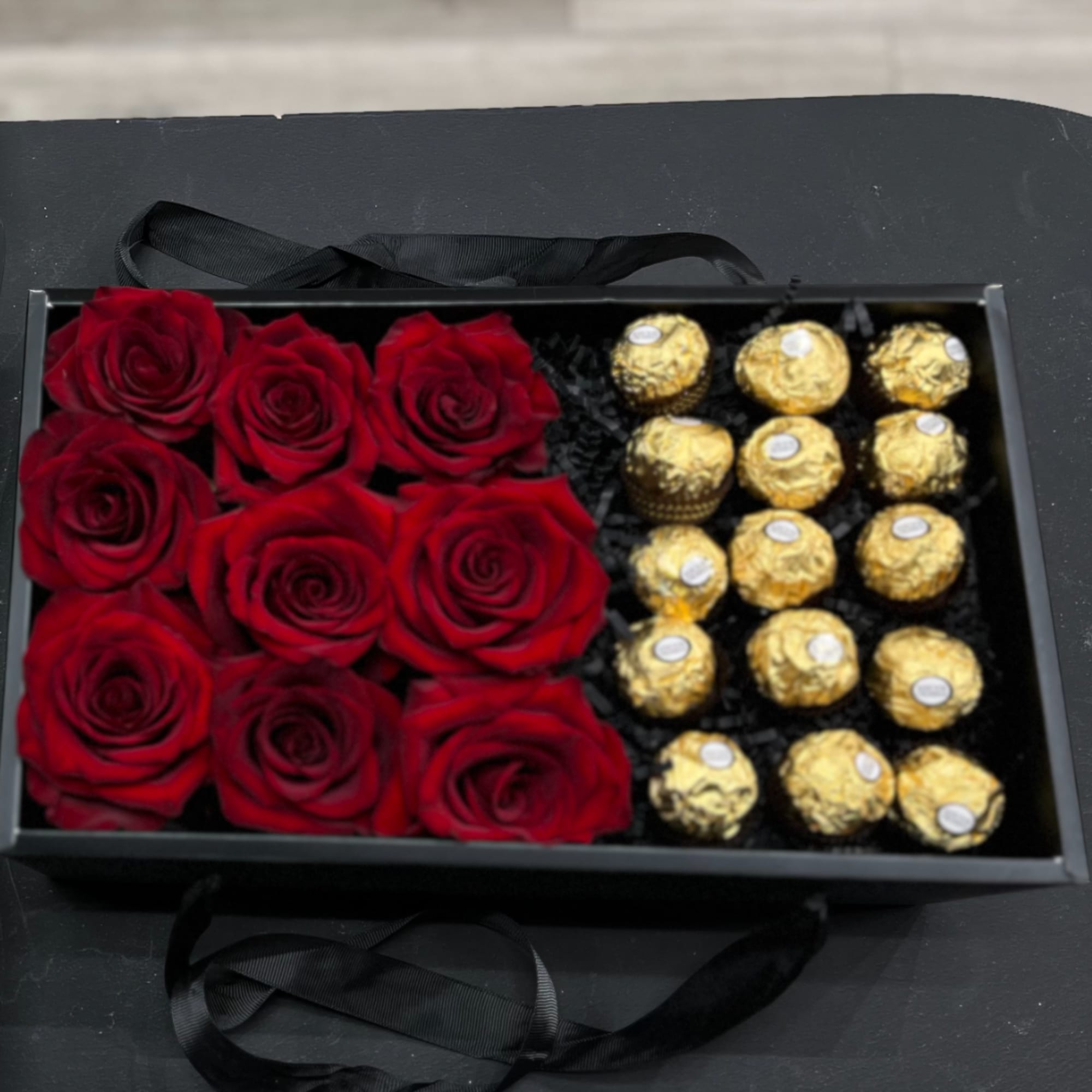 Red roses and gold-wrapped chocolates in a black gift box
