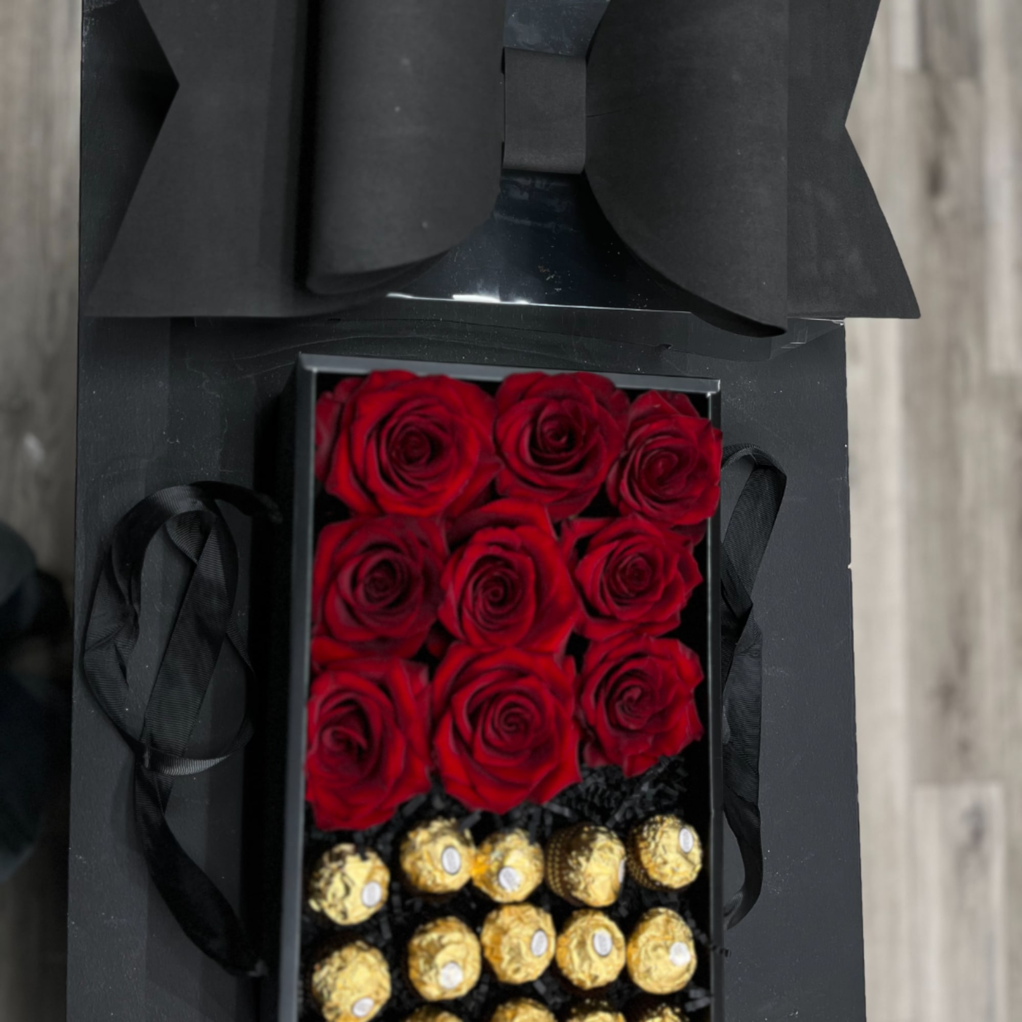 Black gift box with red roses and gold-wrapped chocolates