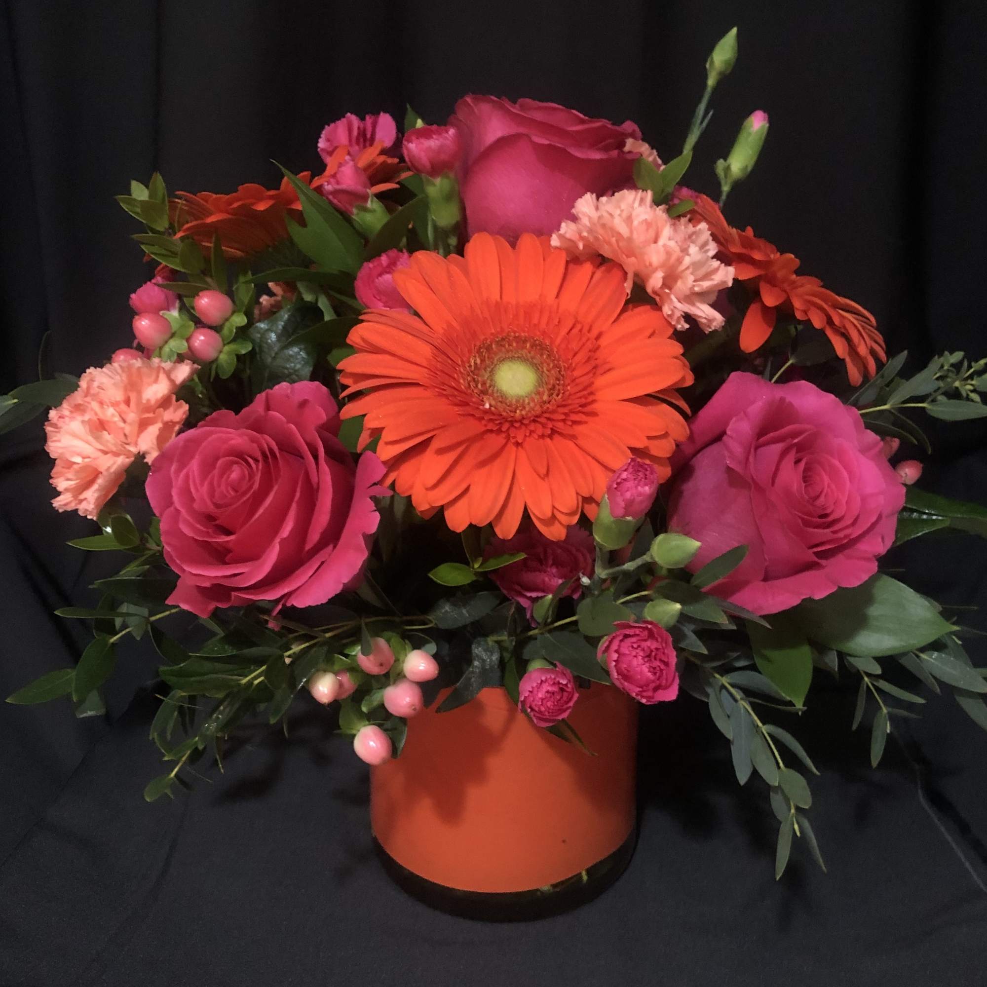 Pink and orange mixed flower arrangement in an orange vase