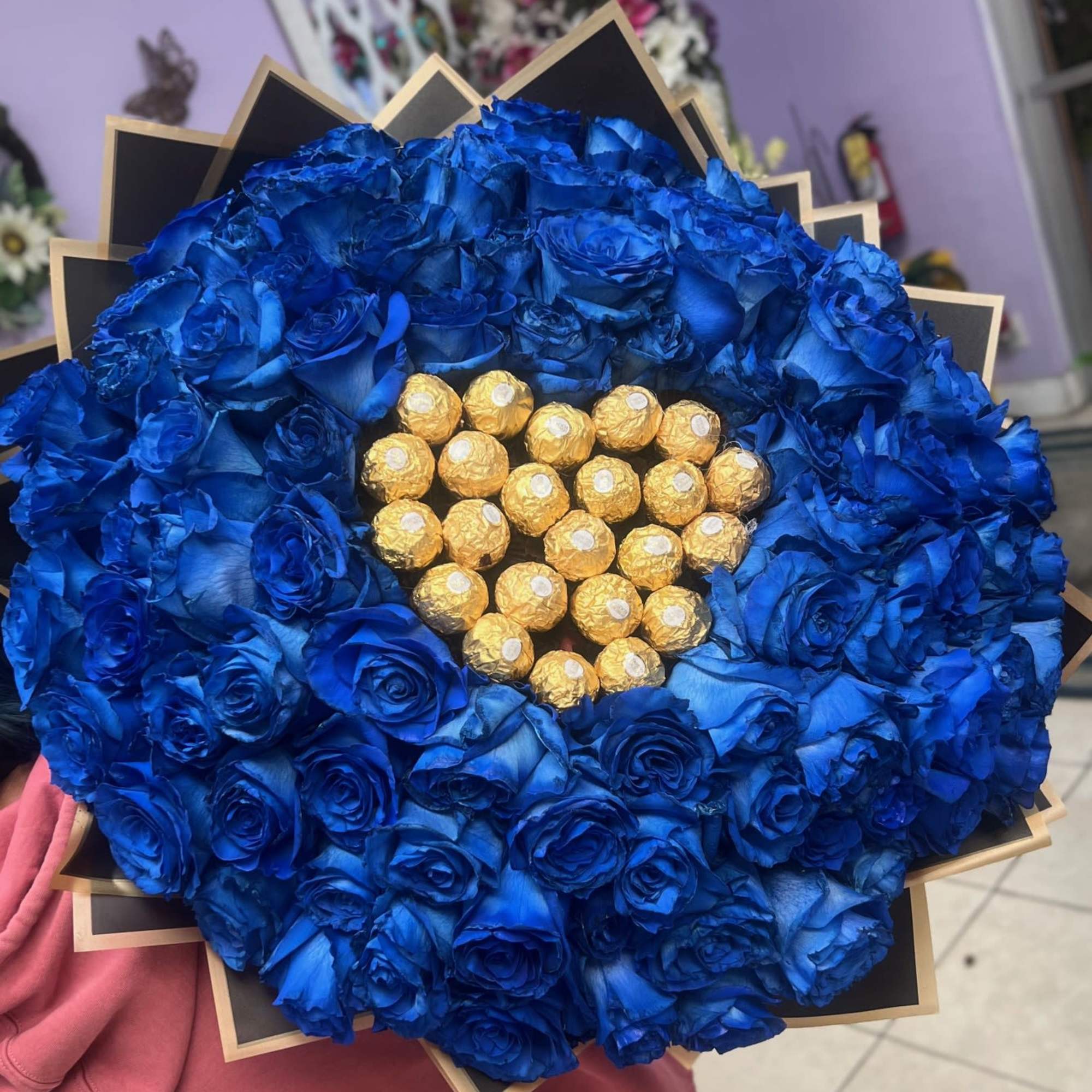 Large bouquet of blue roses with gold-wrapped chocolates in the center