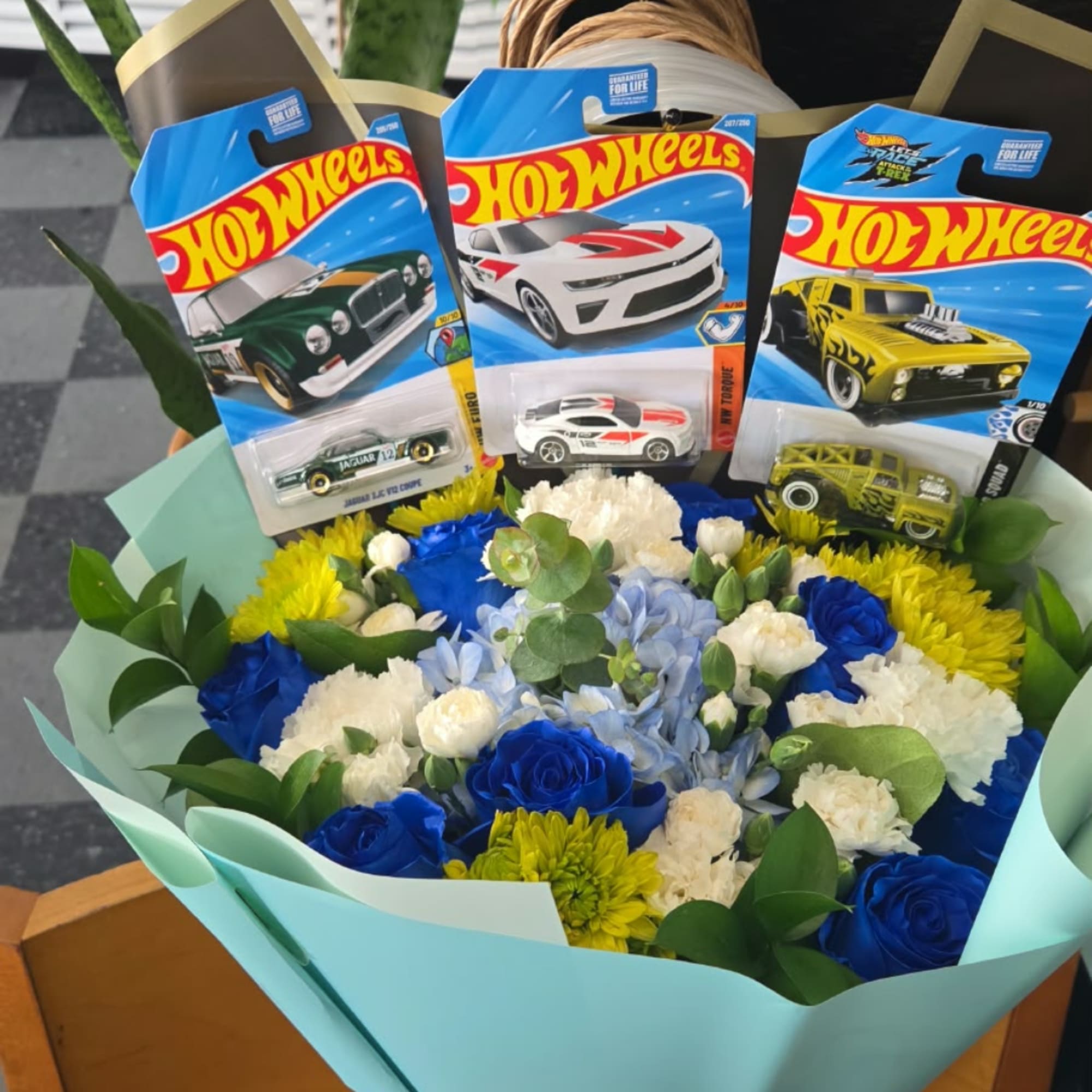 Bouquet of blue, white, and yellow flowers with Hot Wheels toy cars, photo 2 of 4