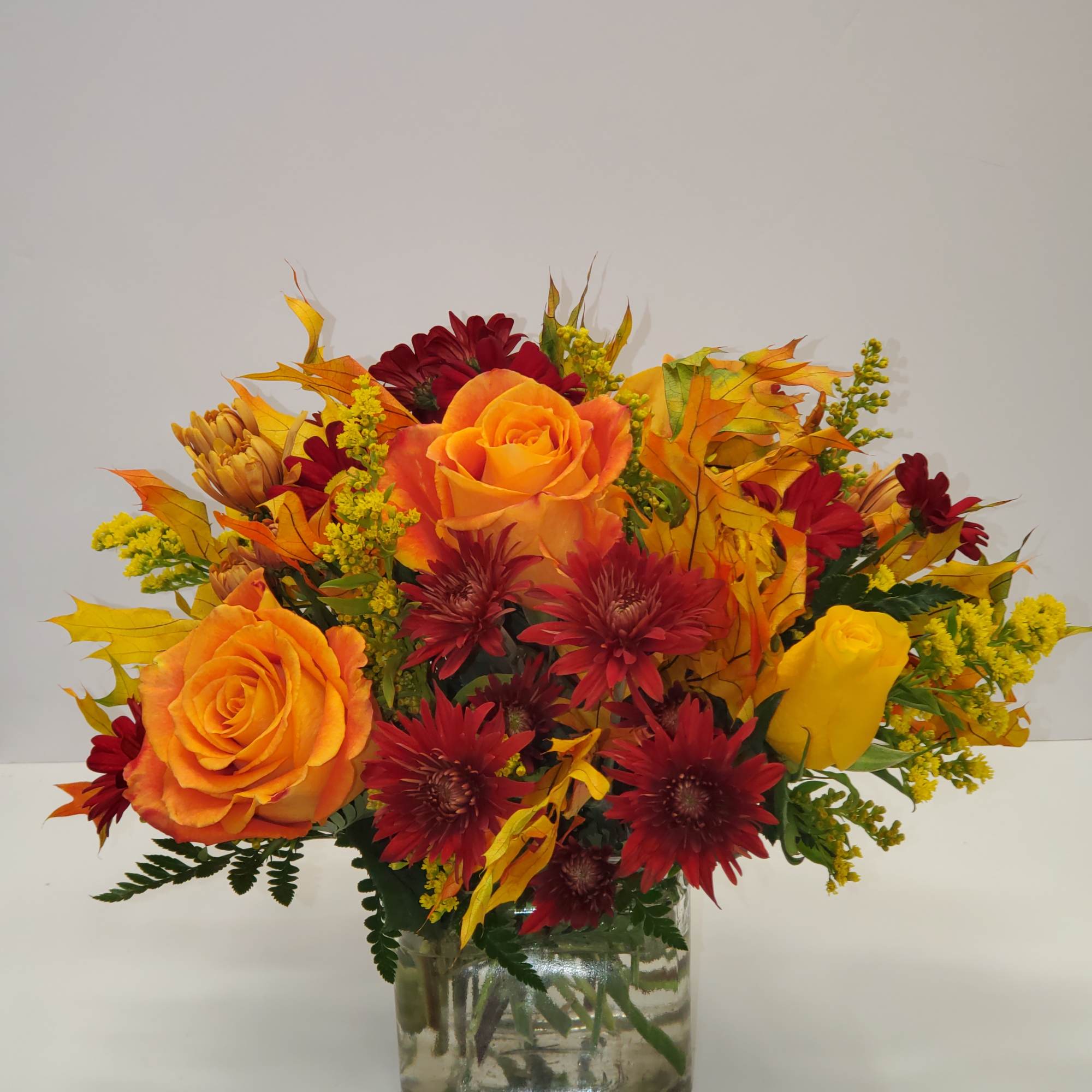 Orange and red flower arrangement in a clear glass vase, photo 2 of 2