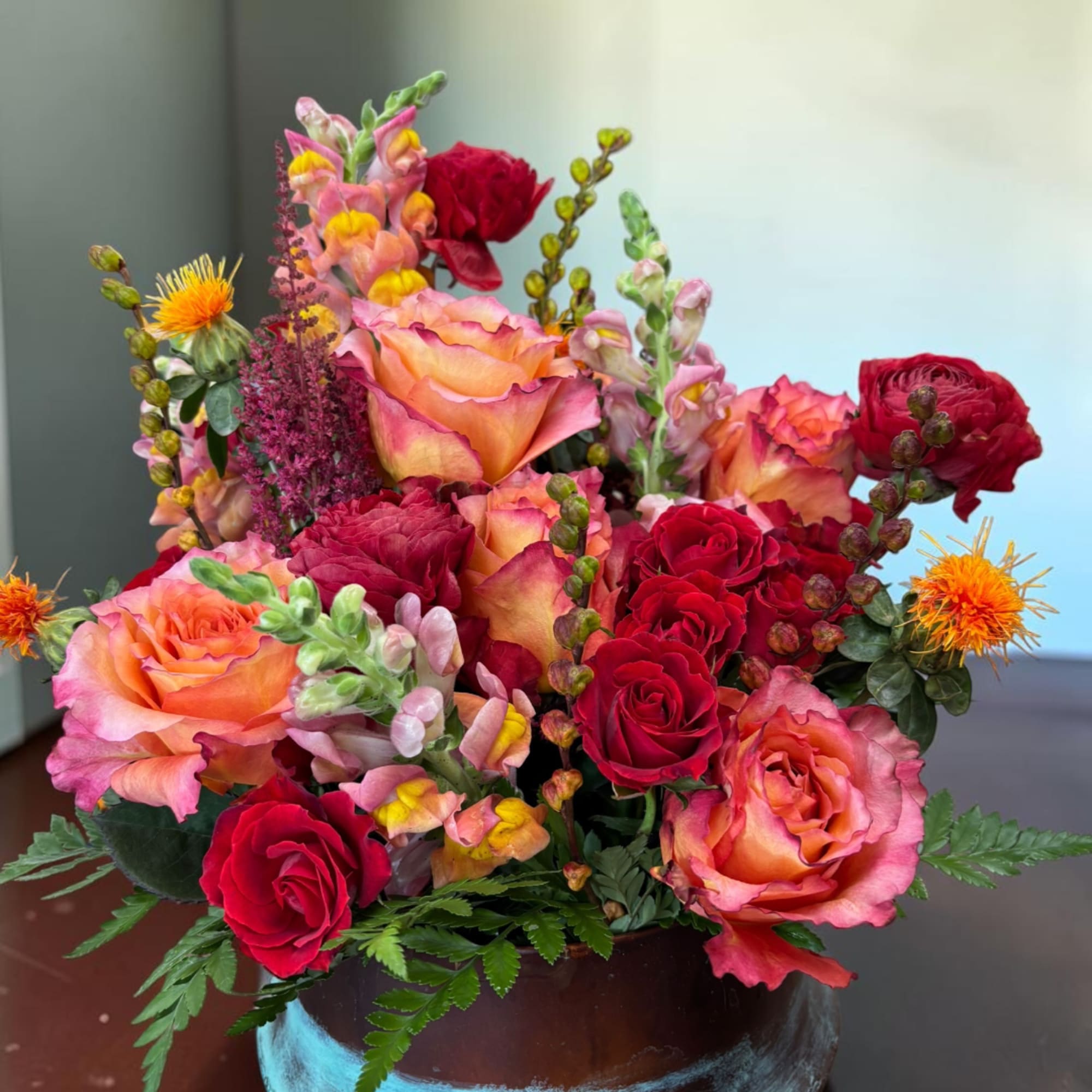 Mixed bouquet of red and peach roses in a dark vase