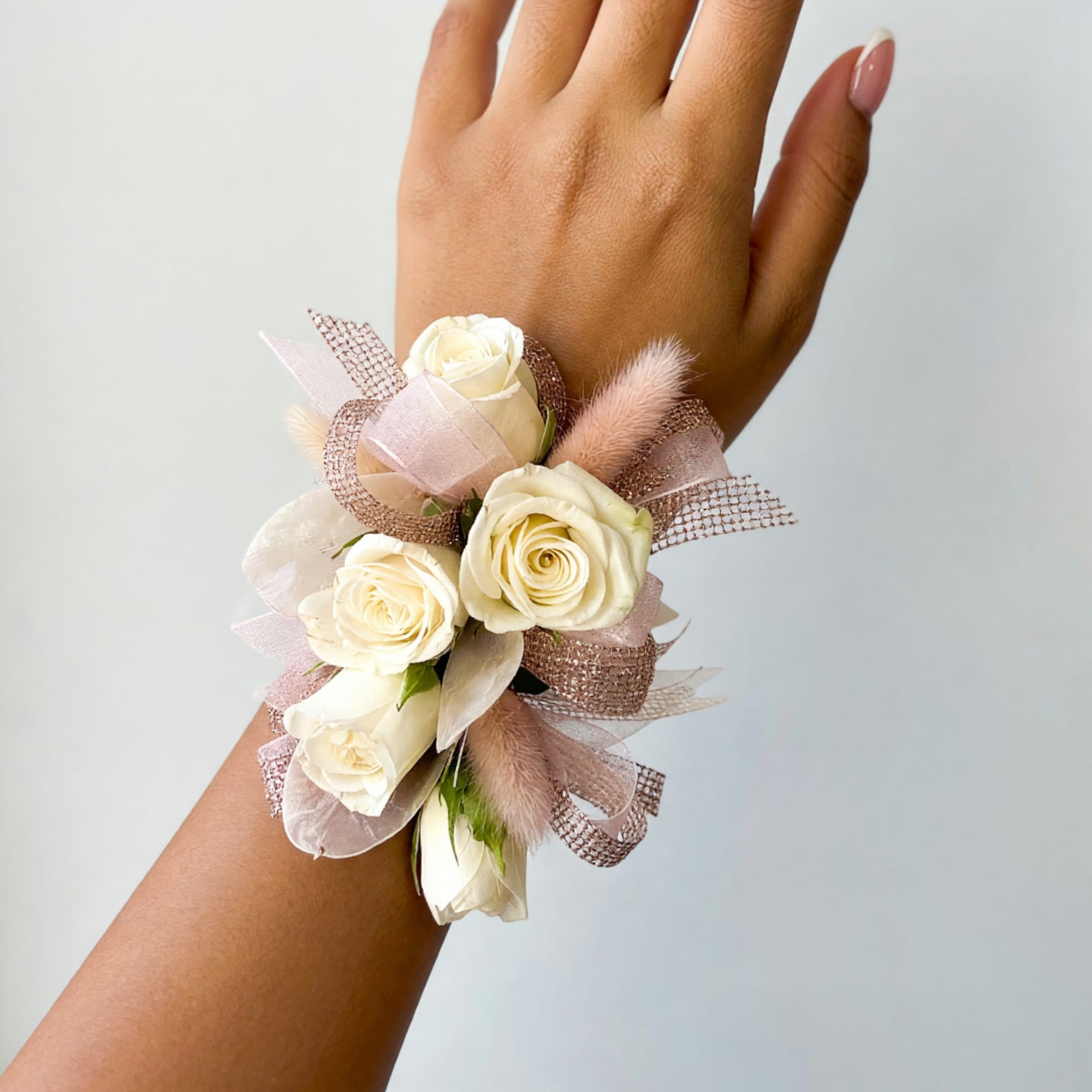 Cream rose wrist corsage with pink ribbon and soft feather accents