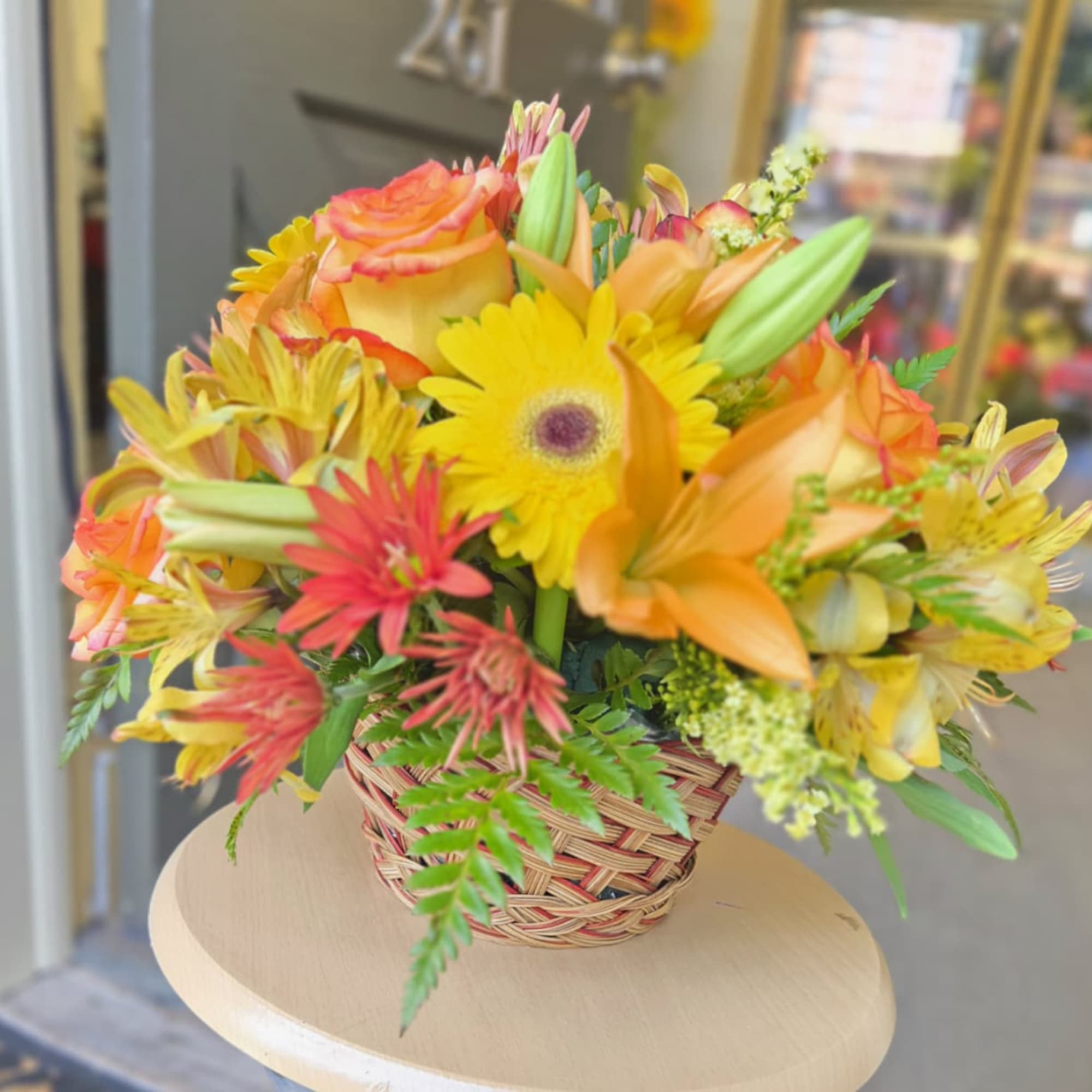 Mixed bouquet of yellow and orange flowers in a woven basket