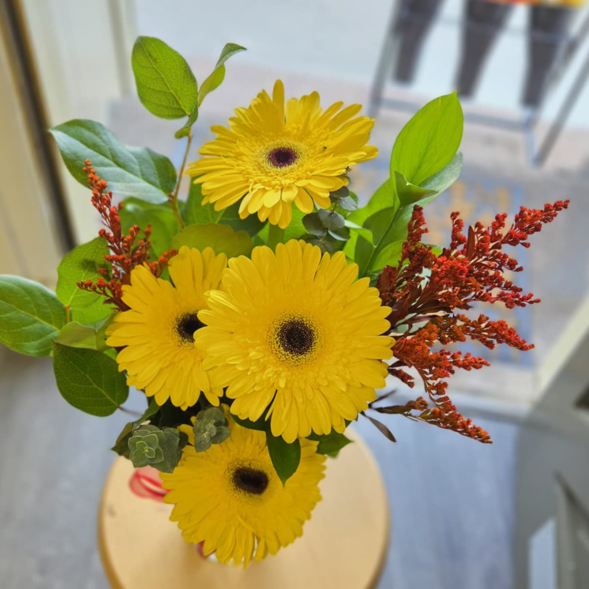 Bouquet of yellow gerbera daisies with red filler flowers