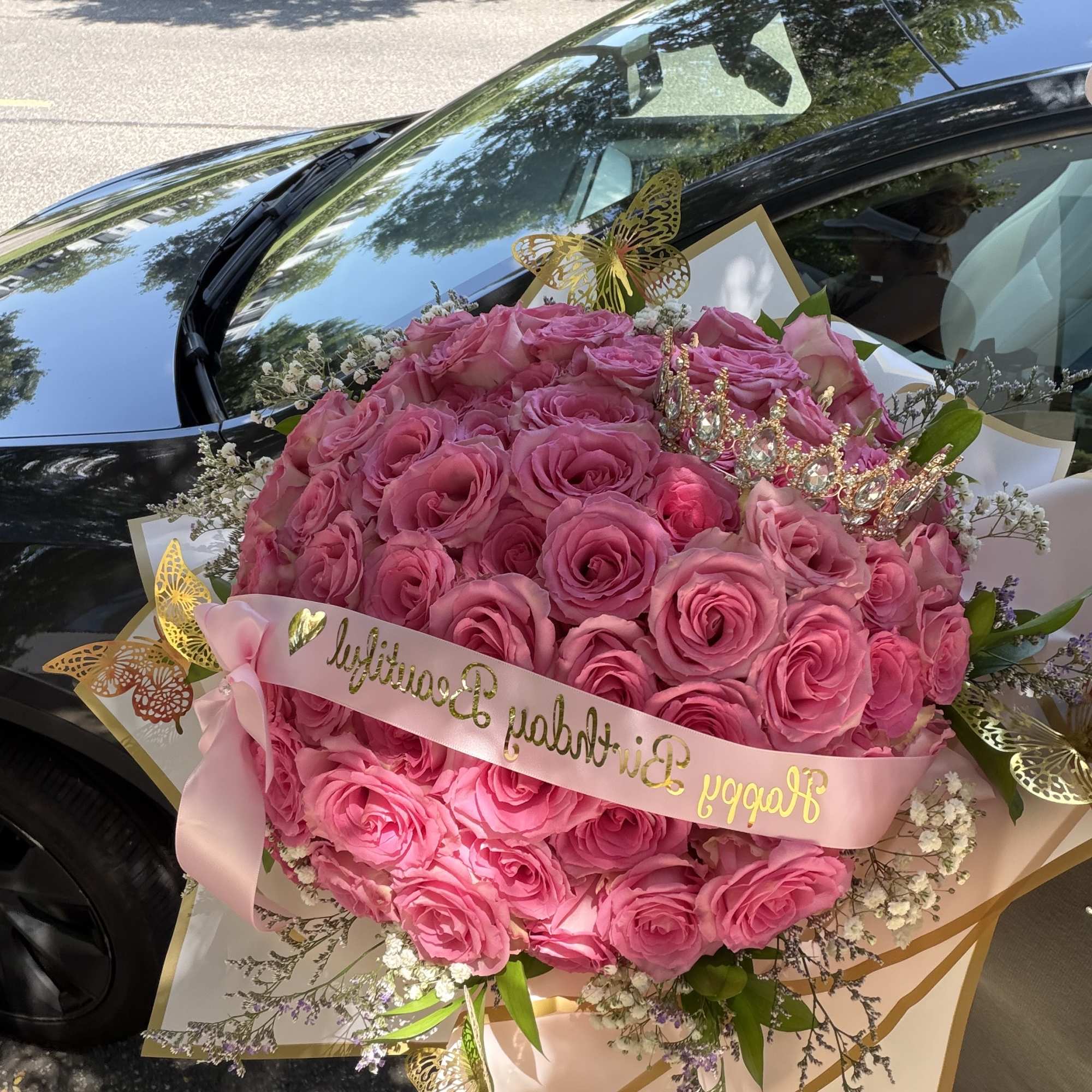 Large bouquet of pink roses with a pink ribbon and gold butterfly accents