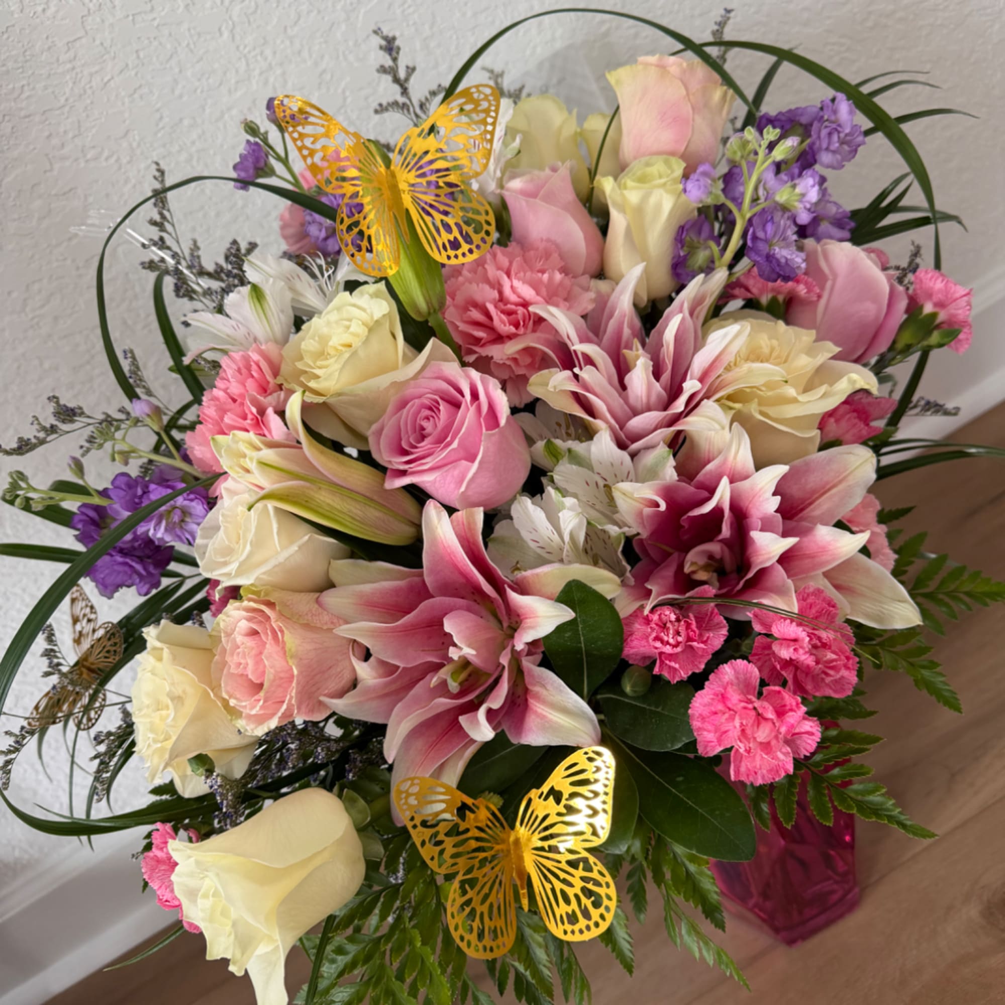 Pink and cream mixed bouquet with lilies, roses, and purple accents in a vase