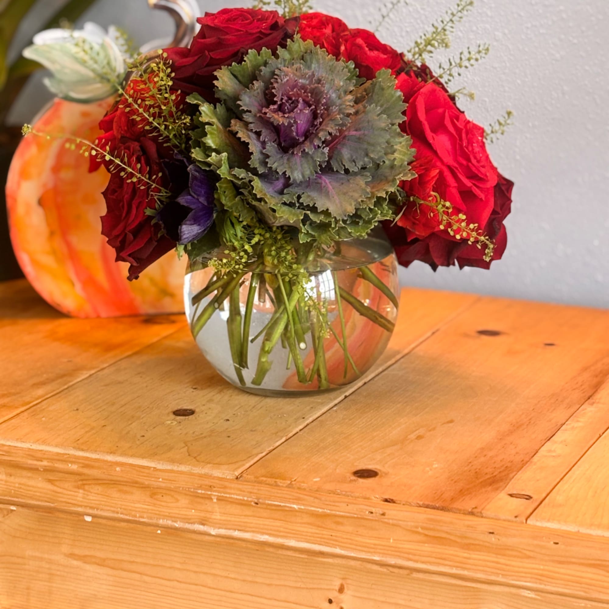 Red roses and purple ornamental cabbage in a glass vase