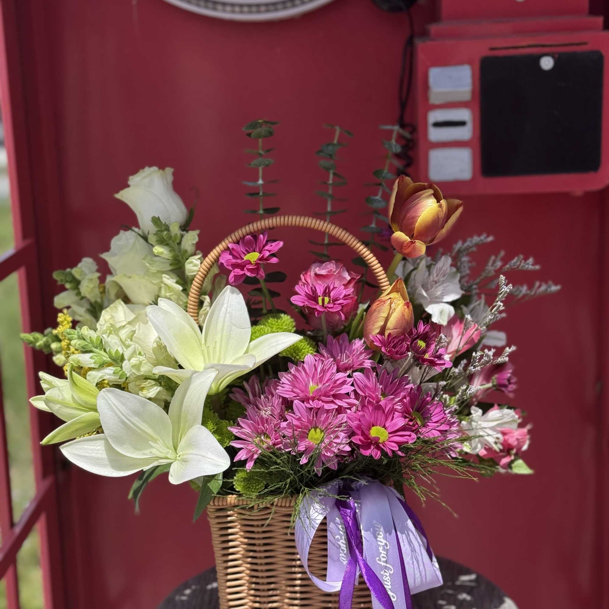 Basket arrangement of white lilies and pink daisies with a purple ribbon