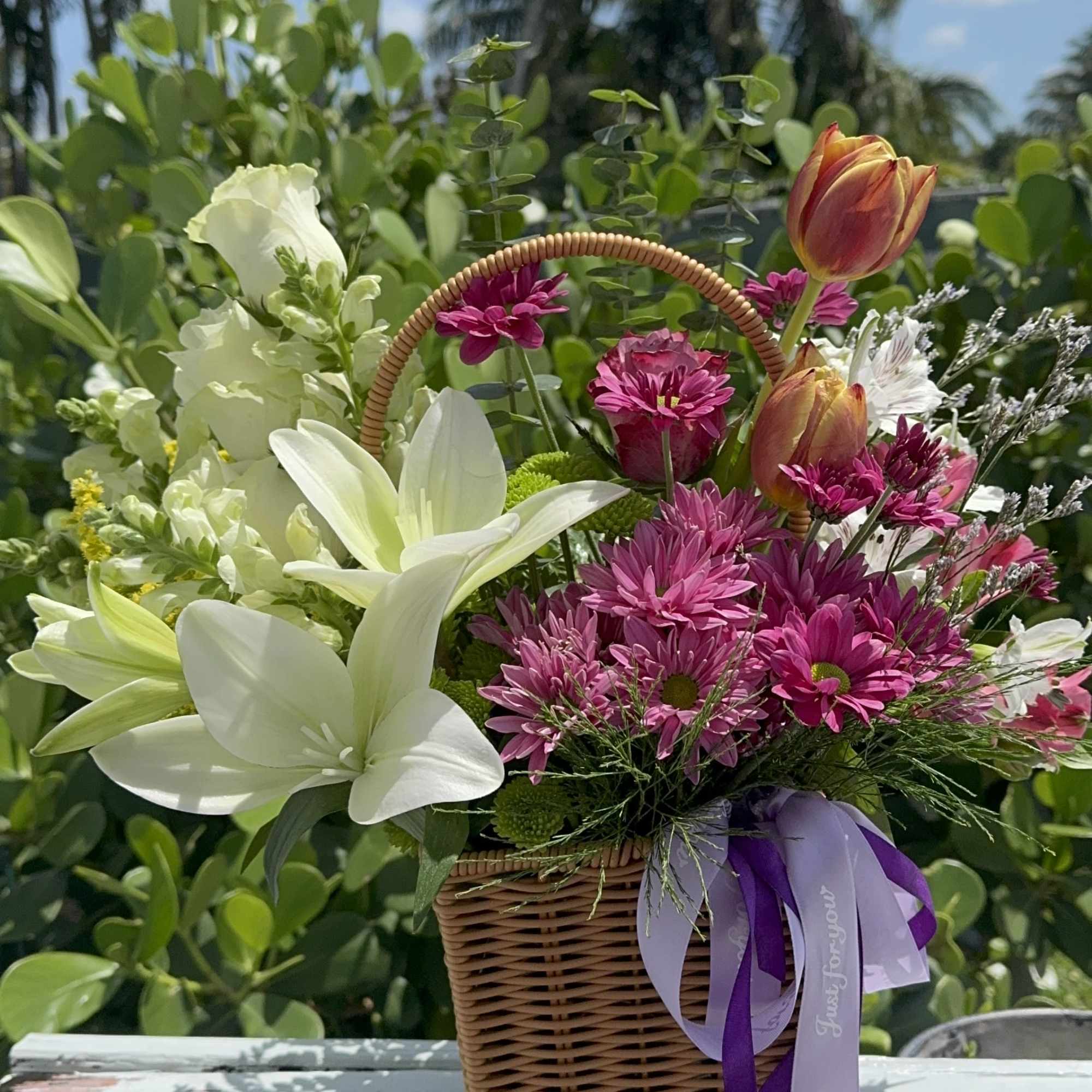 Basket of pink and white flowers with tulips and daisies