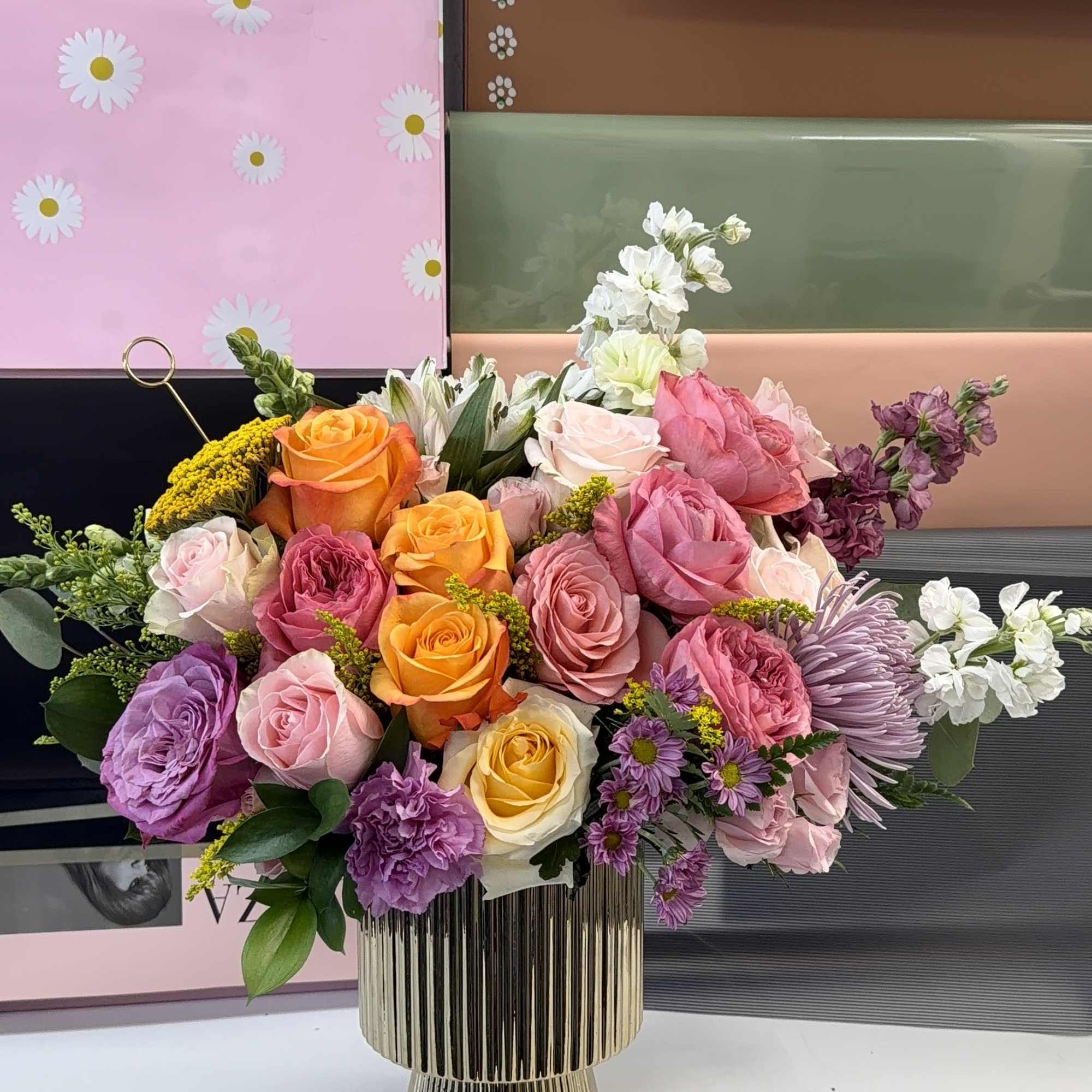 Mixed bouquet of roses and purple blooms in a gold vase