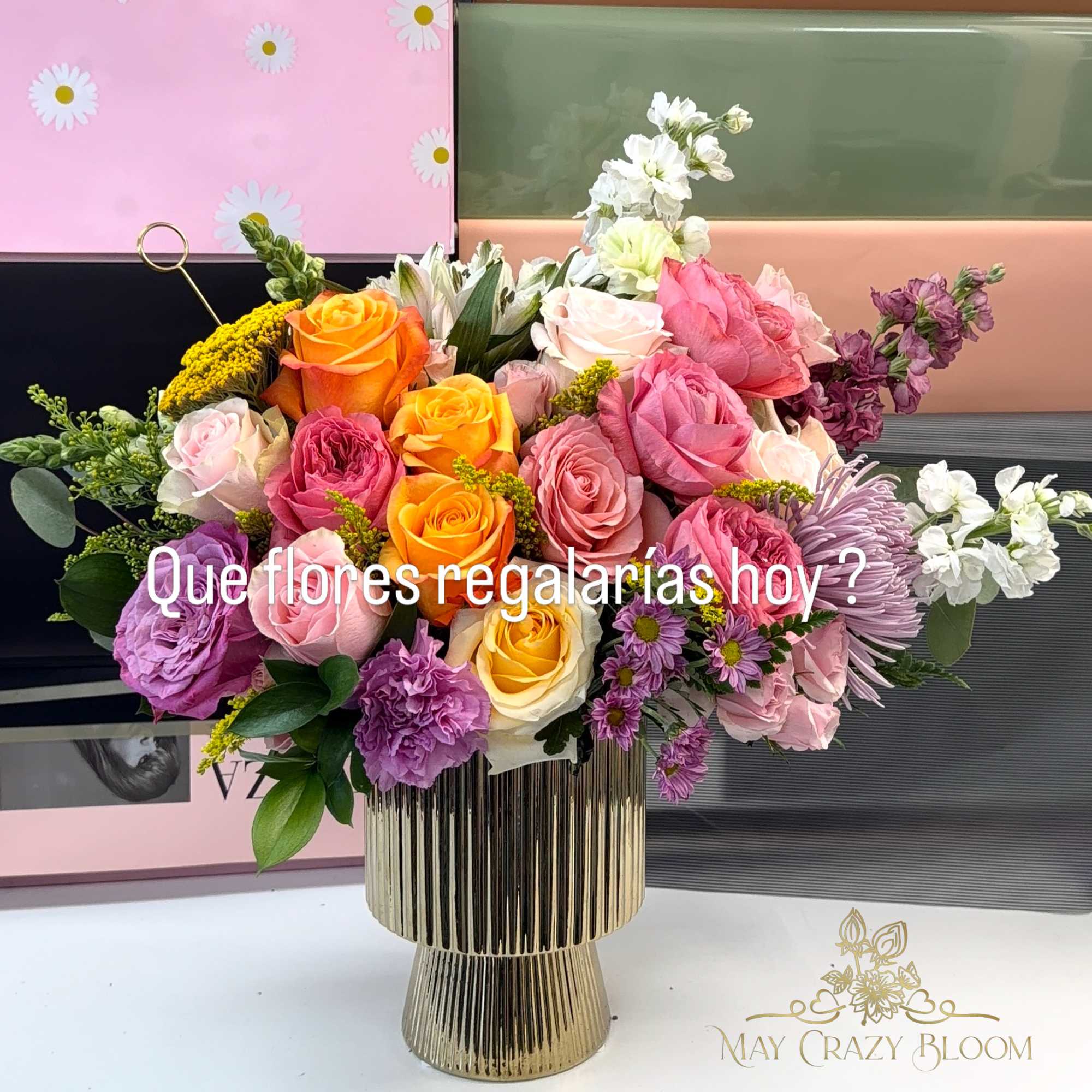 Mixed bouquet of roses, lilies, and purple blooms in a gold vase