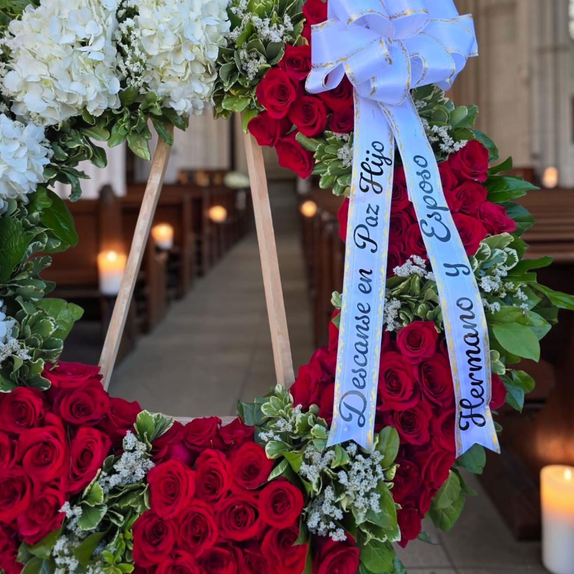 Floral wreath of red and white roses with a white ribbon bow