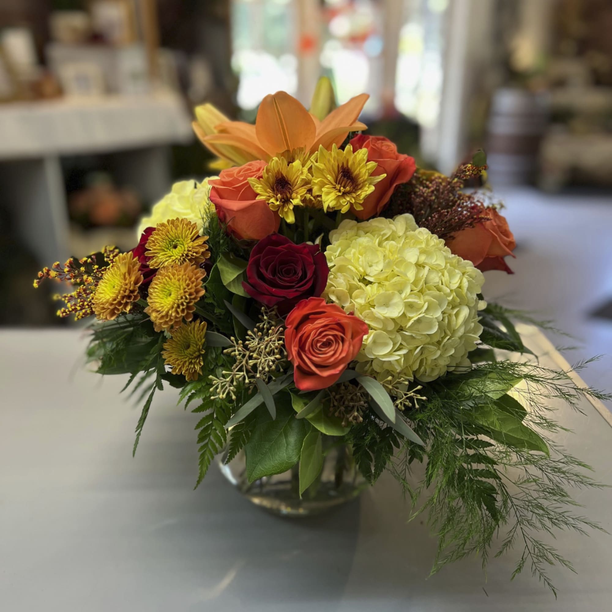 Mixed bouquet of roses, lilies, and hydrangea in a glass vase