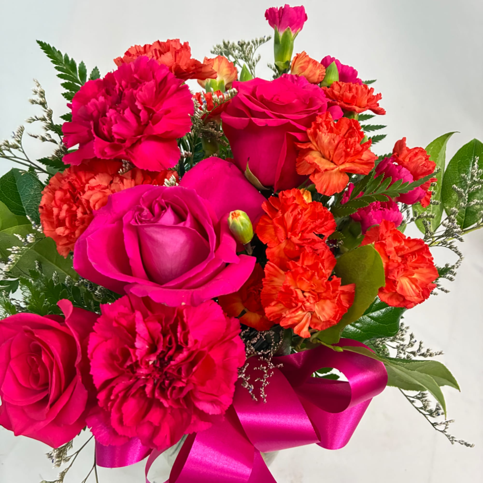 Hot pink roses and orange carnations with a satin ribbon