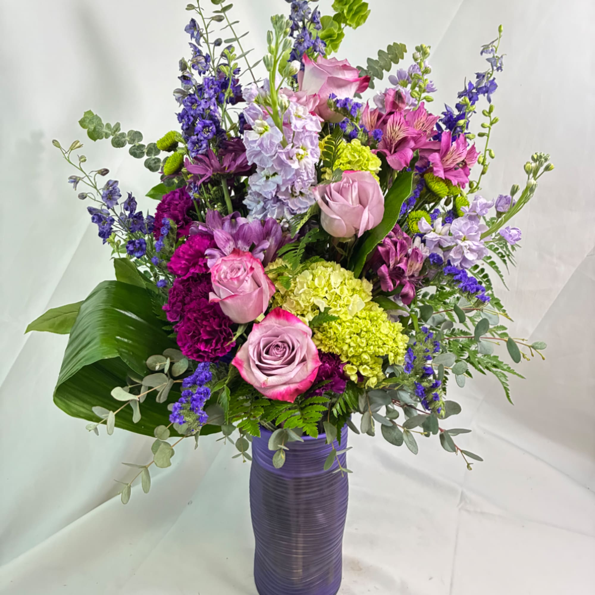 Tall bouquet of pink and purple flowers in a purple vase