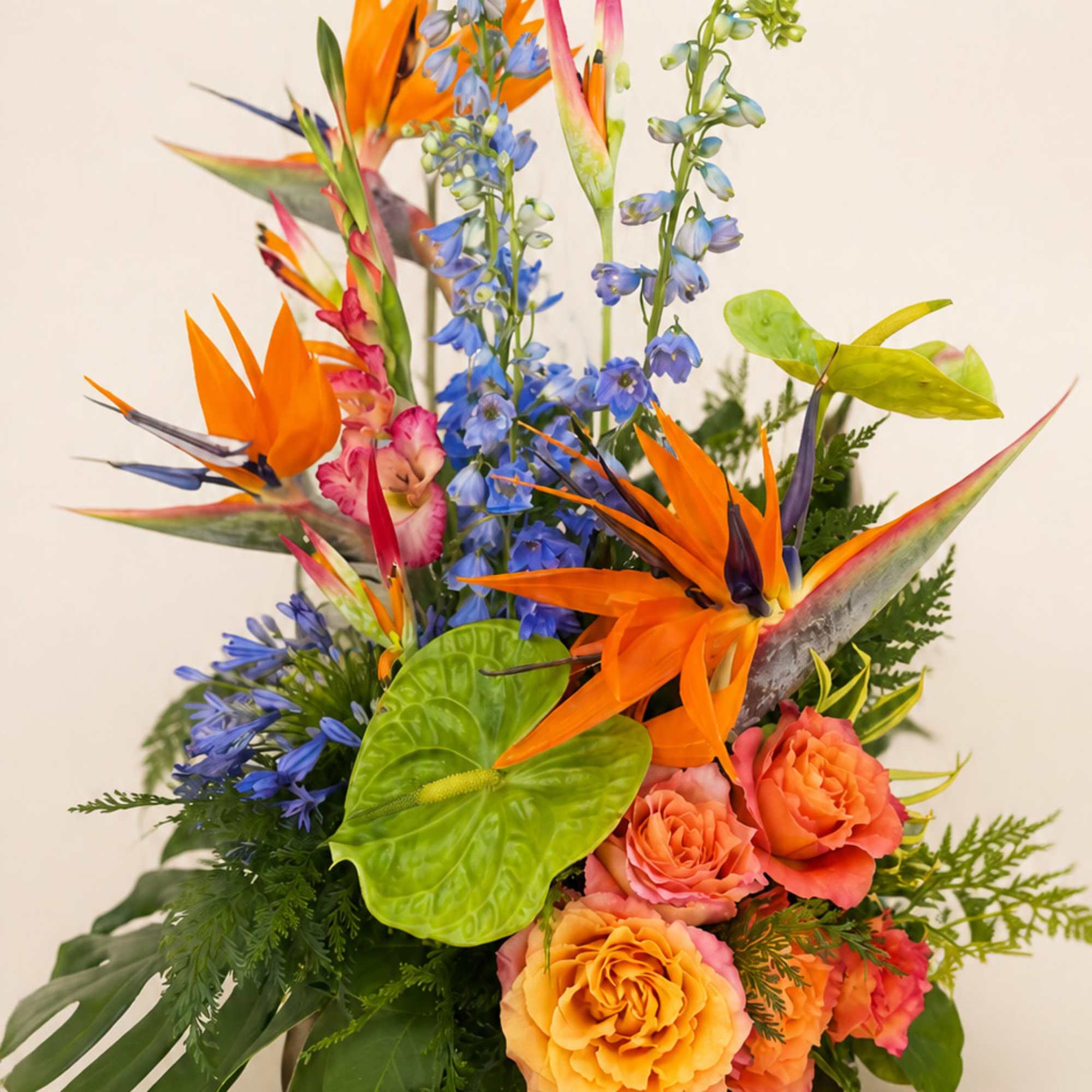 Tropical bouquet with orange bird-of-paradise, blue flowers, and coral roses