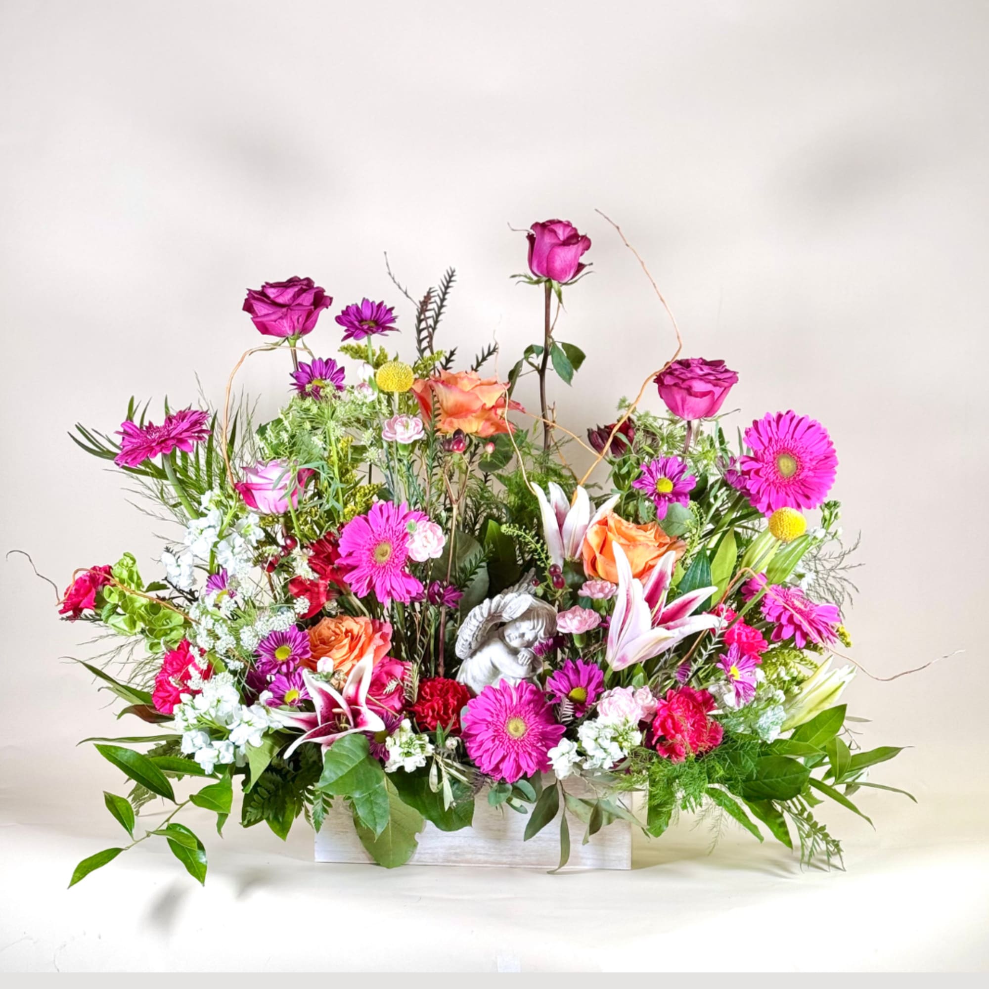 Mixed pink and orange floral arrangement in a white container