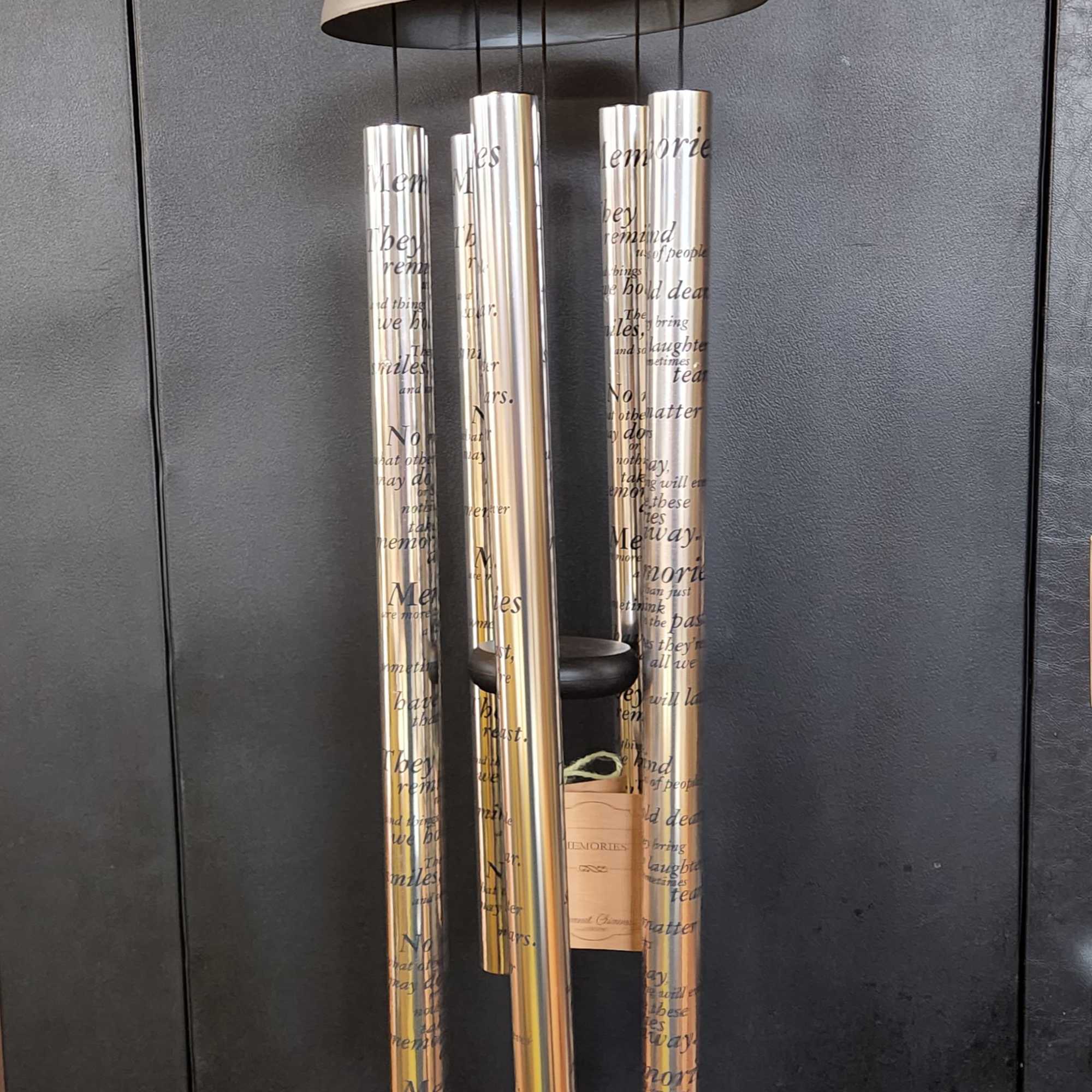 Hanging metal wind chime with printed memorial text and a small tag