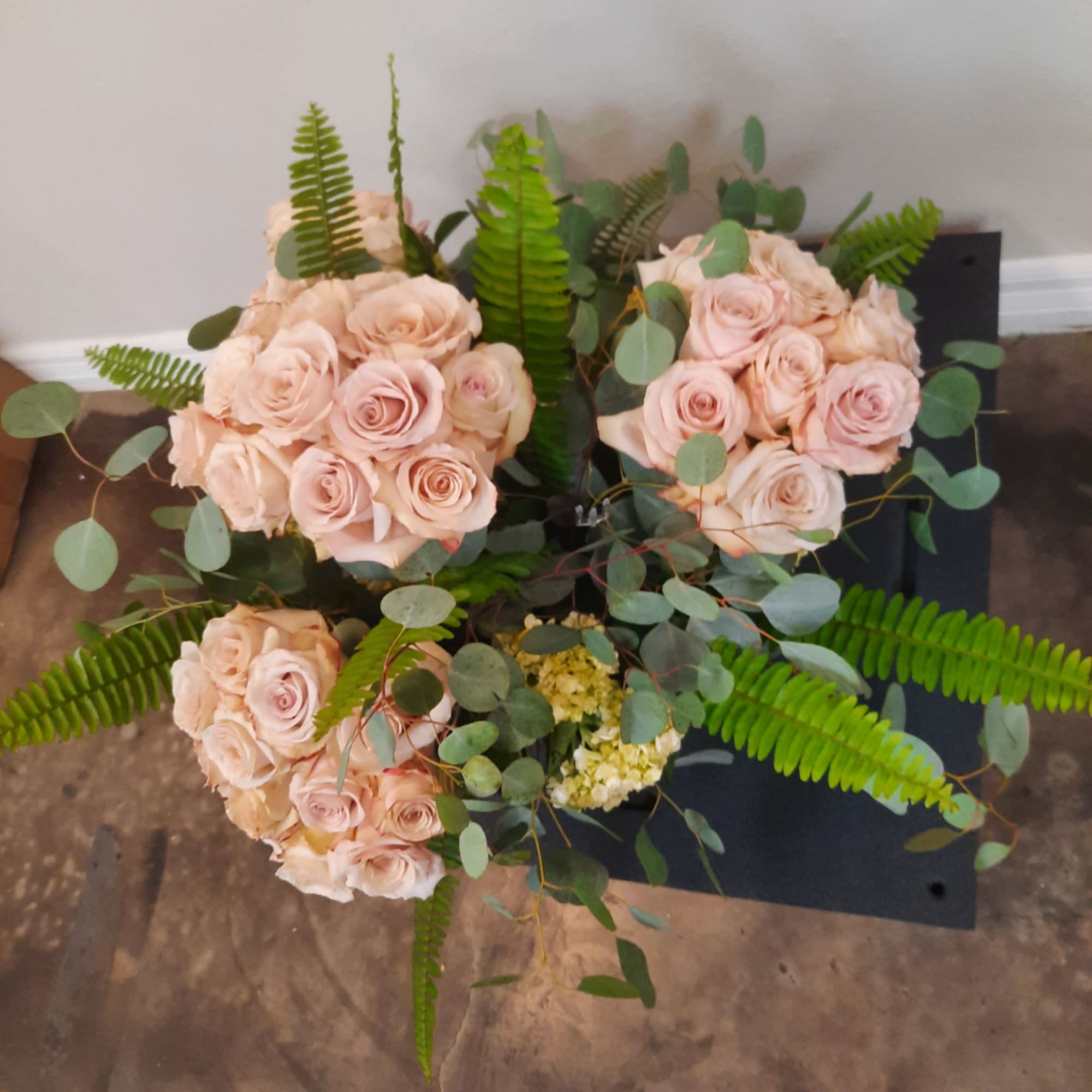 Three pale pink rose bouquets with fern and eucalyptus greenery
