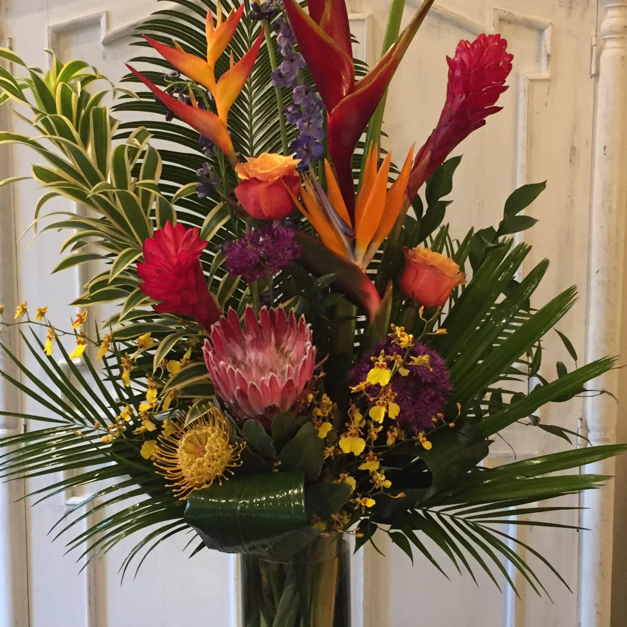 Tropical bouquet with orange heliconia and red ginger in a glass vase