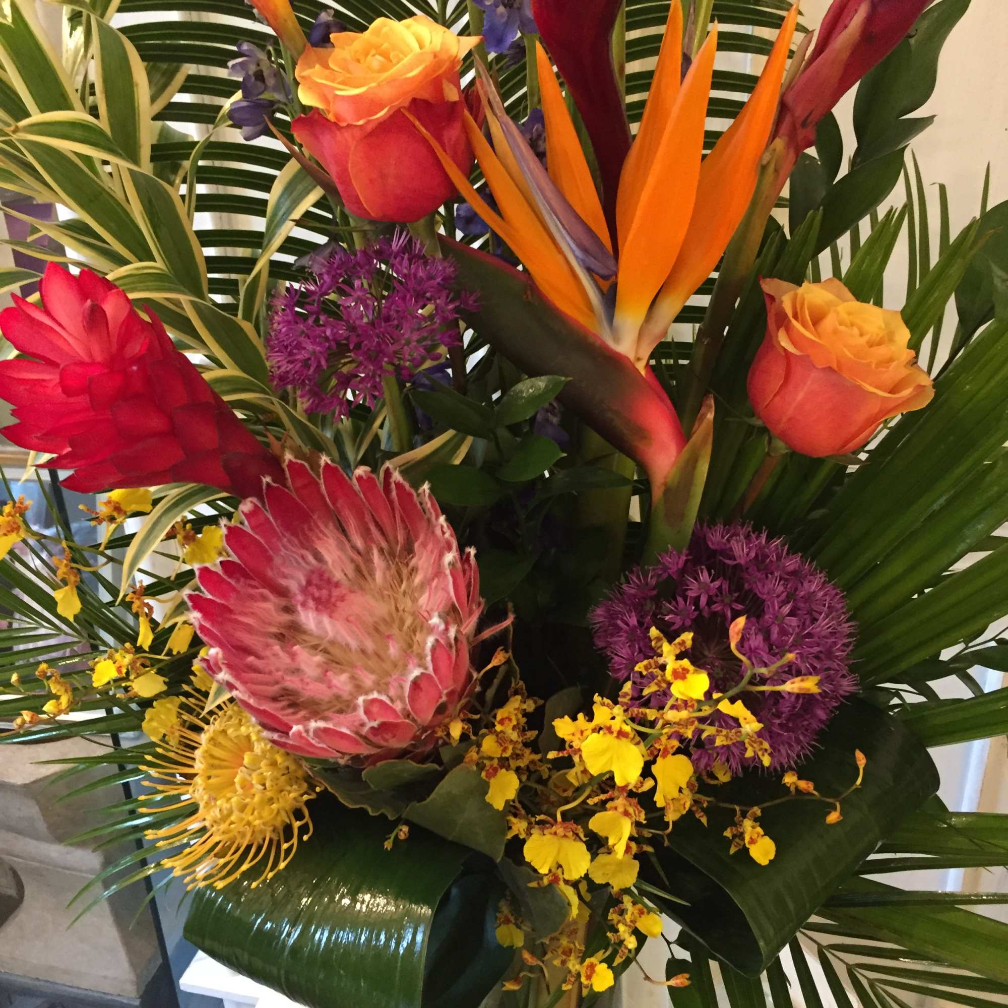 Tropical bouquet with orange bird of paradise, roses, and purple flowers
