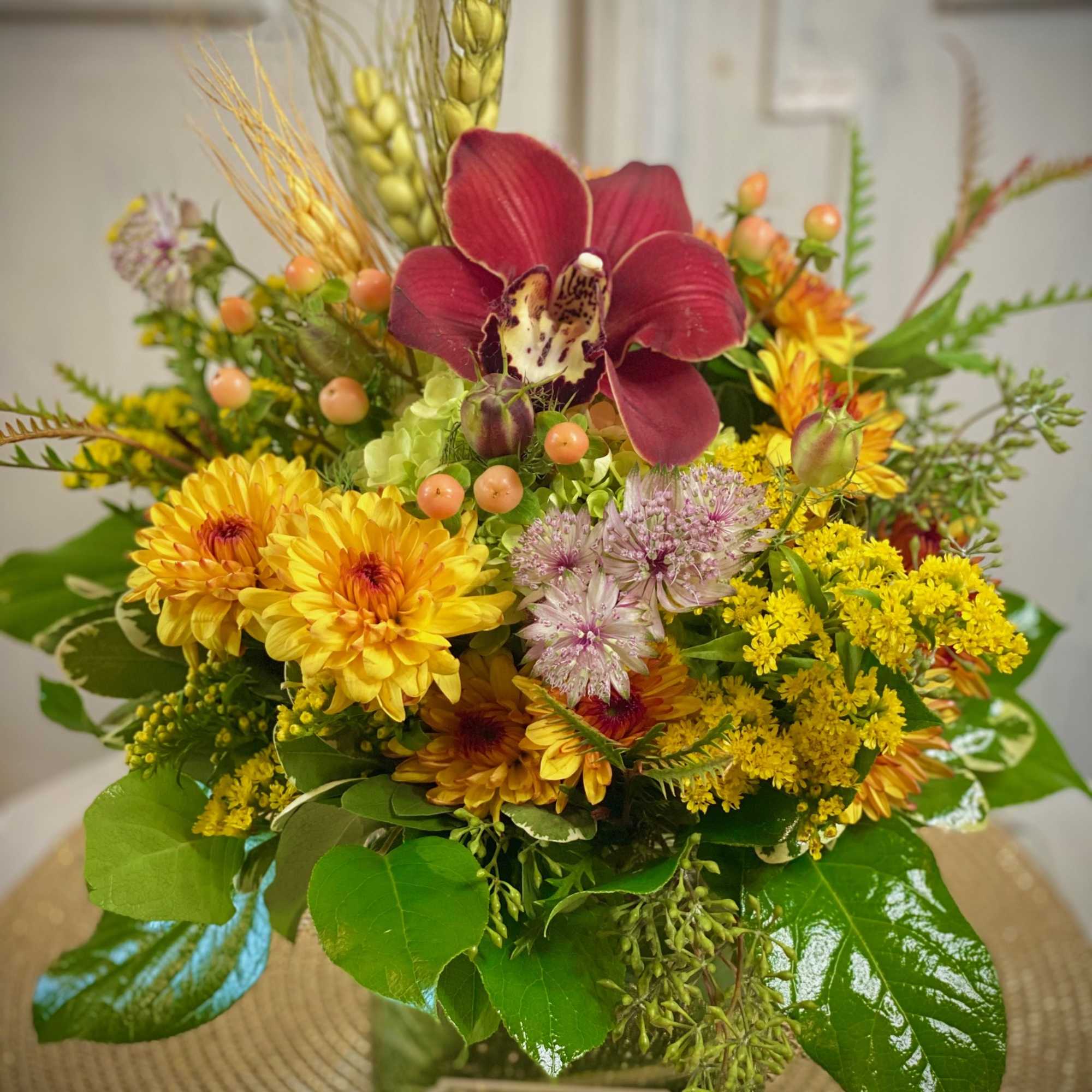Mixed bouquet with a burgundy orchid and yellow chrysanthemums in a glass vase