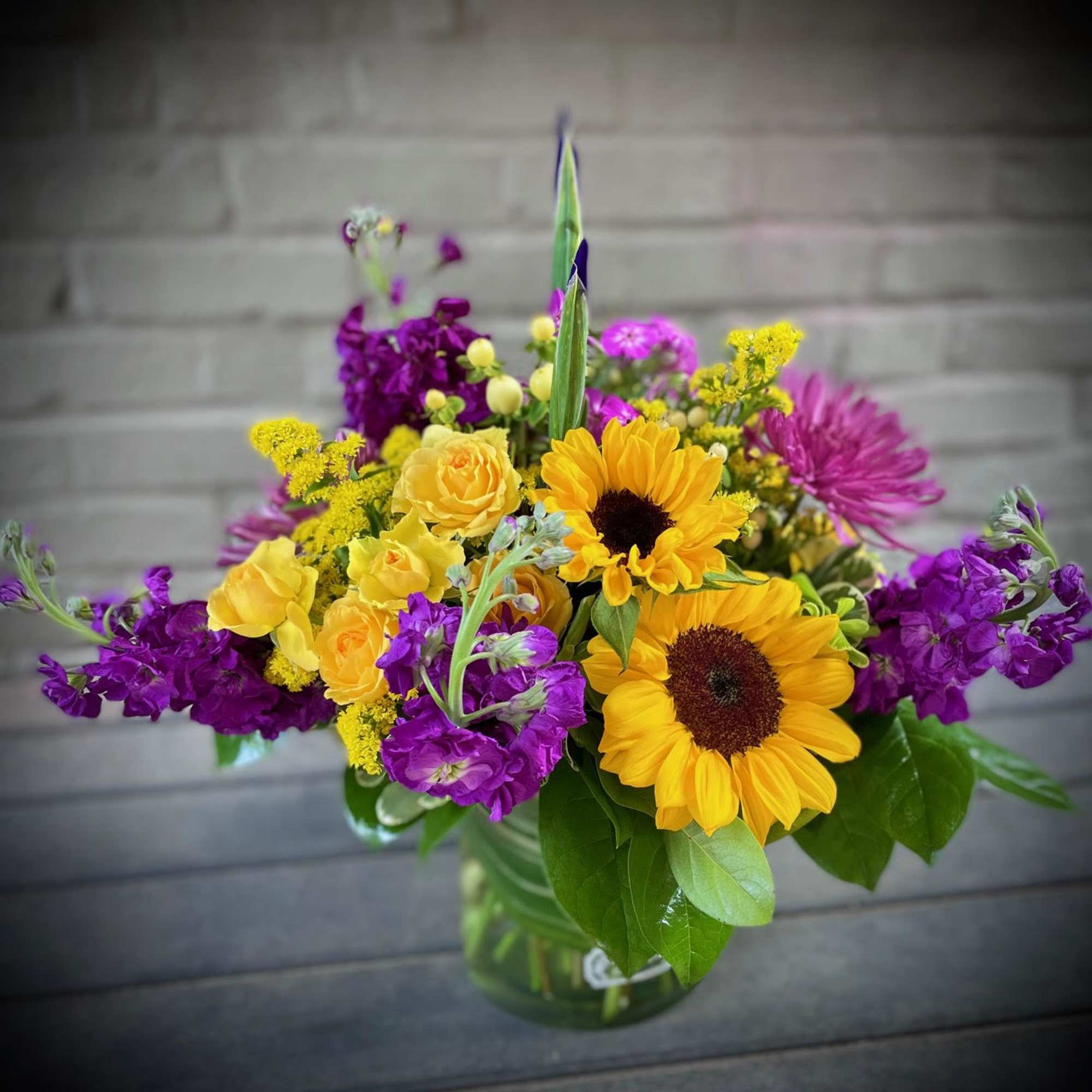 Bouquet of yellow sunflowers and purple flowers in a glass vase
