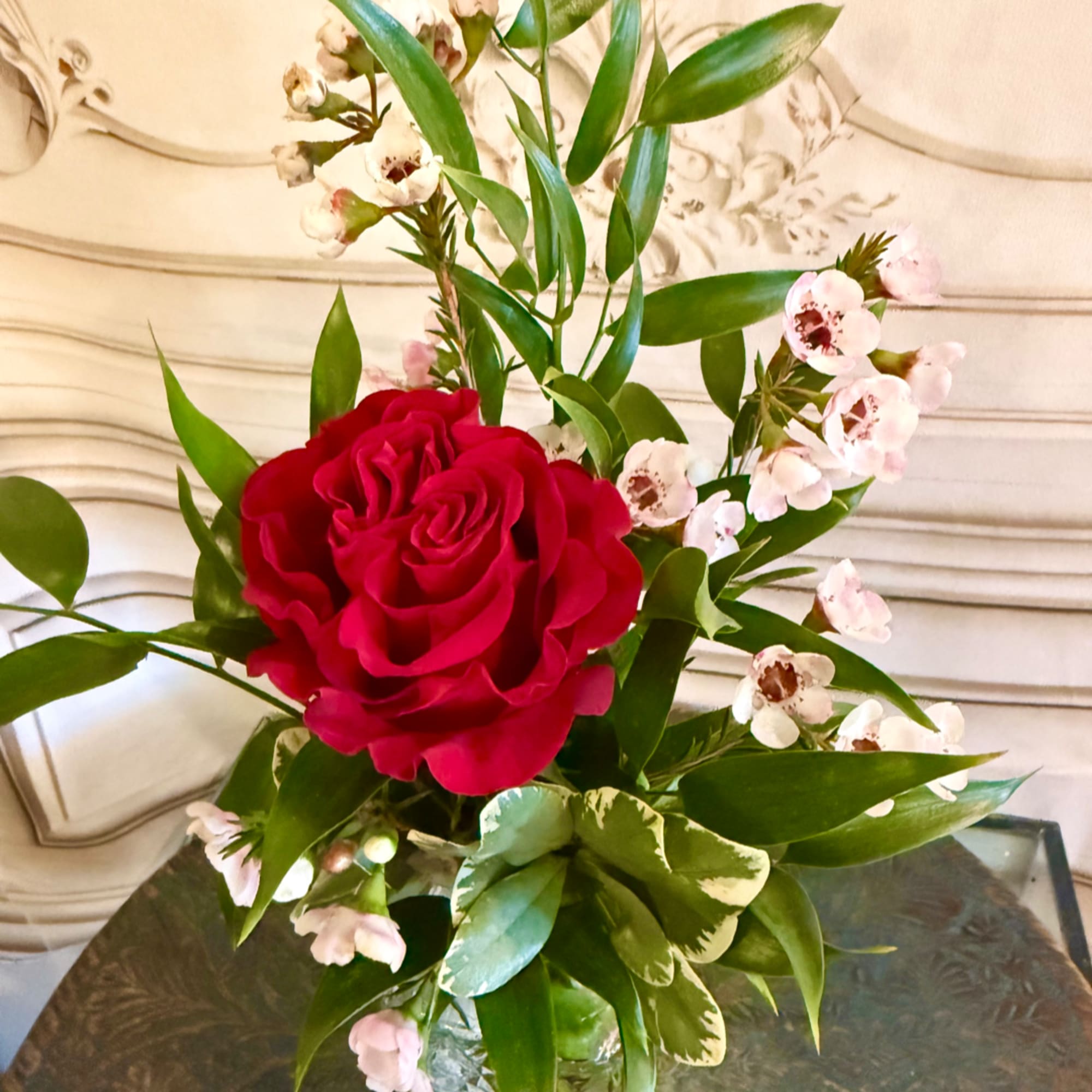 Red rose arrangement with small white blossoms in a glass vase