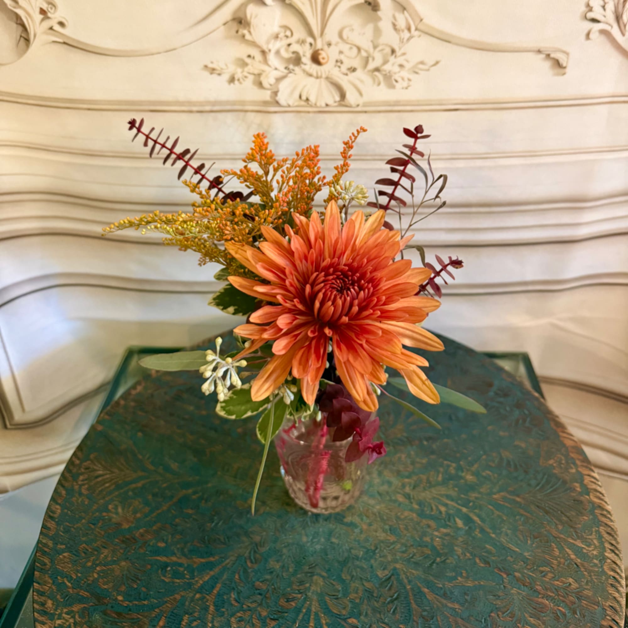 Orange chrysanthemum arrangement in a clear glass vase
