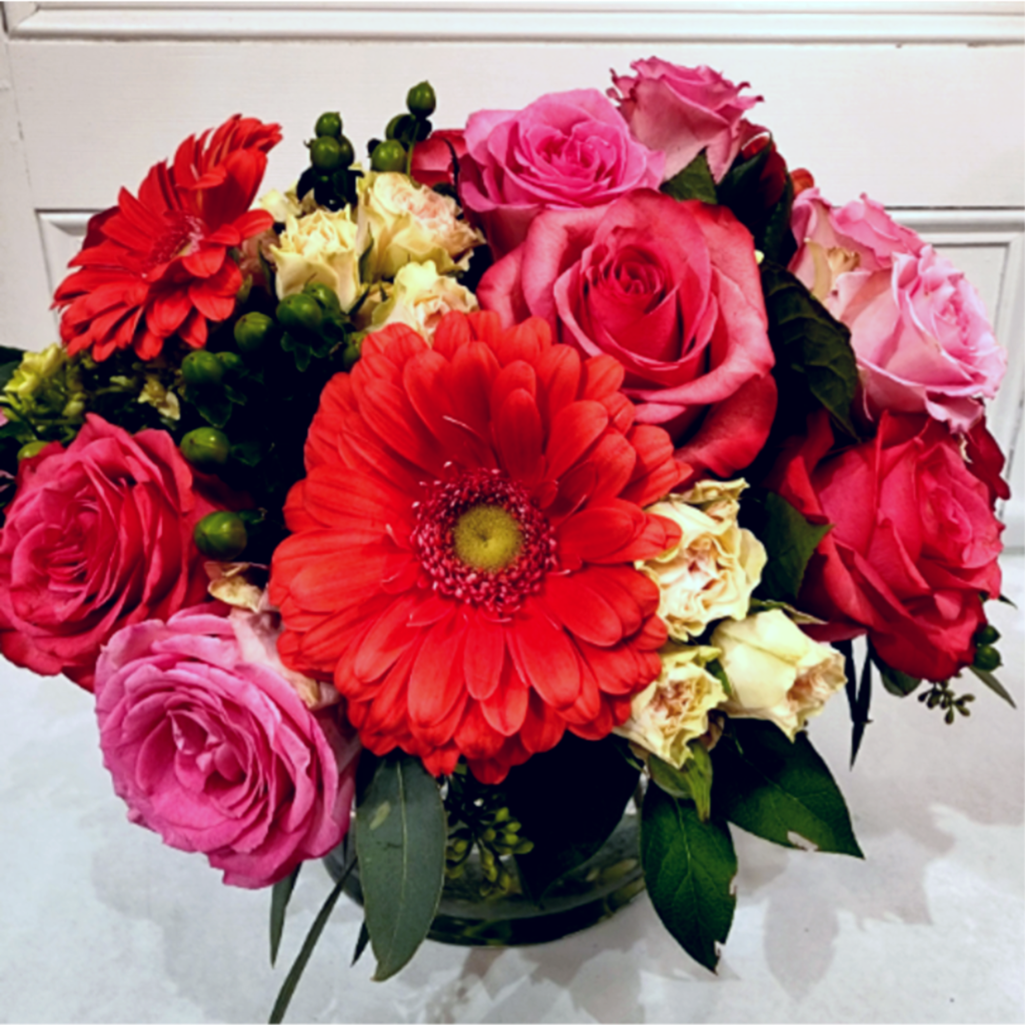 Bouquet of pink and red roses with a red gerbera daisy in a vase