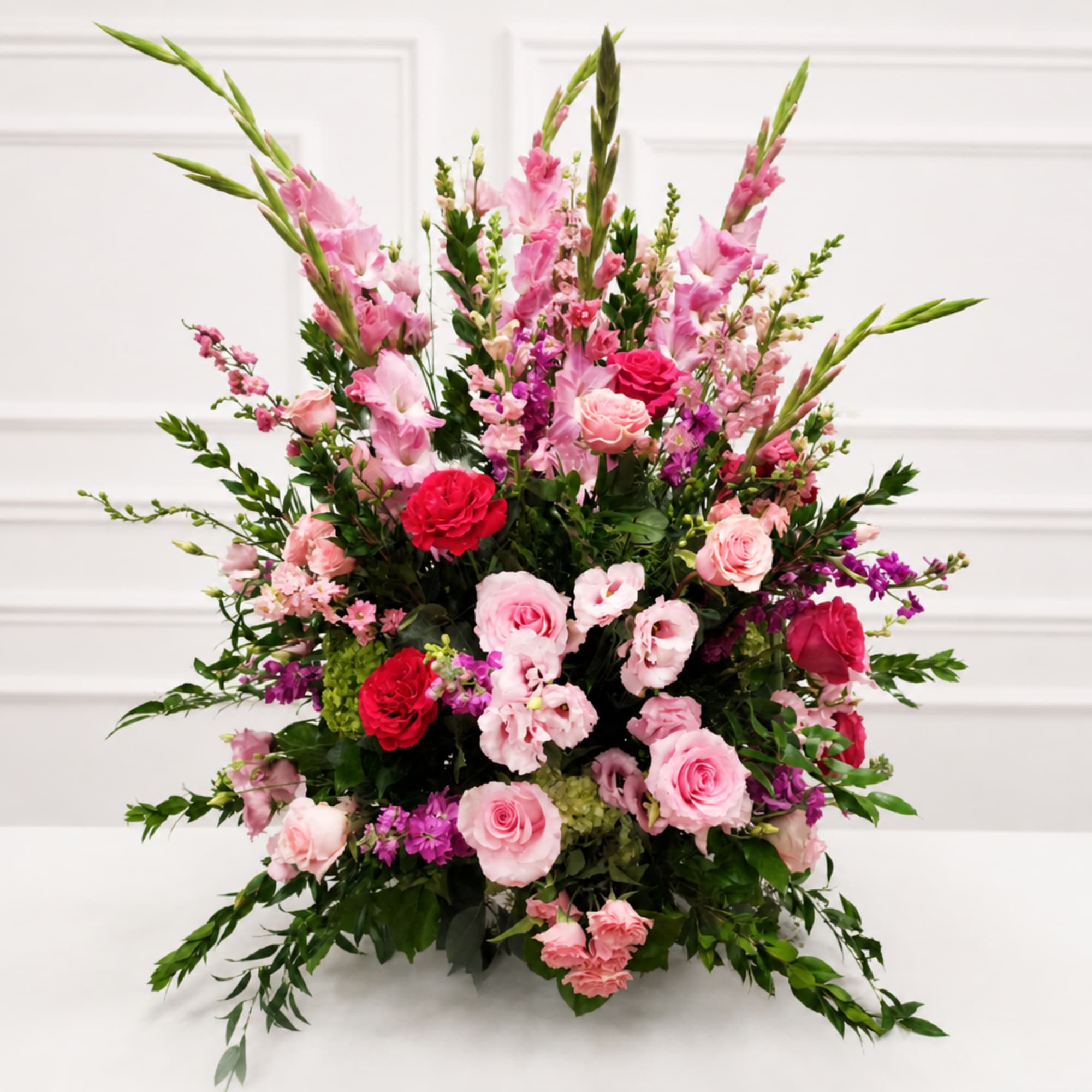 Large pink and red floral arrangement with roses and tall spikes