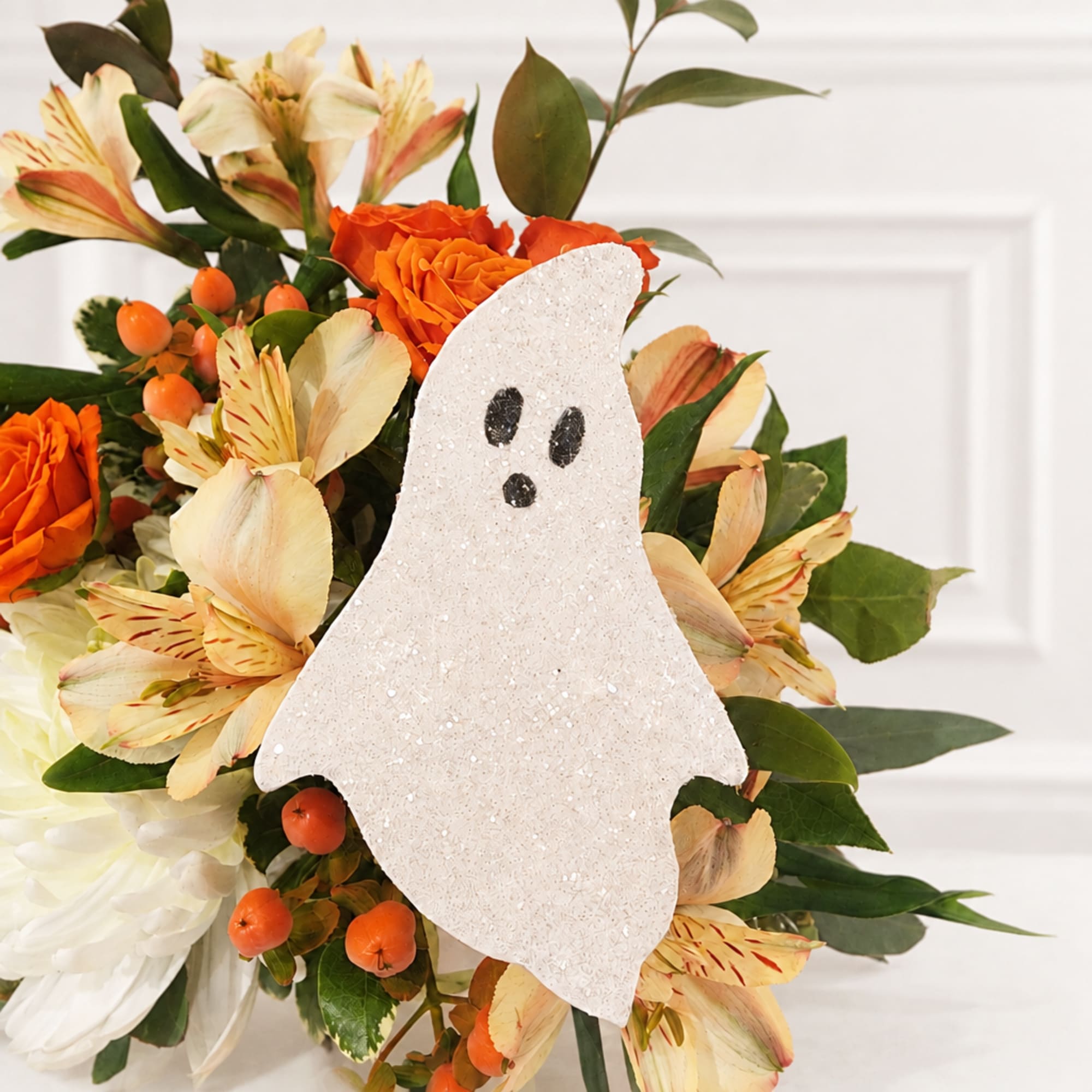 Orange and cream floral arrangement with a glittery ghost decoration