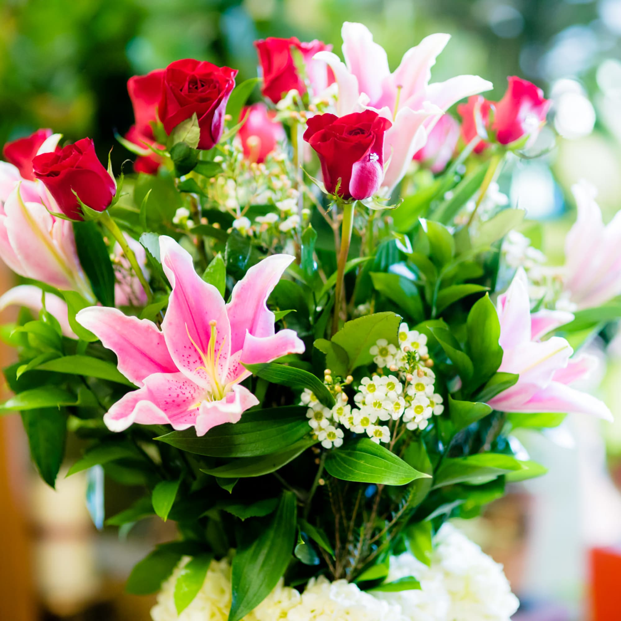 Bouquet of pink lilies and red roses with greenery