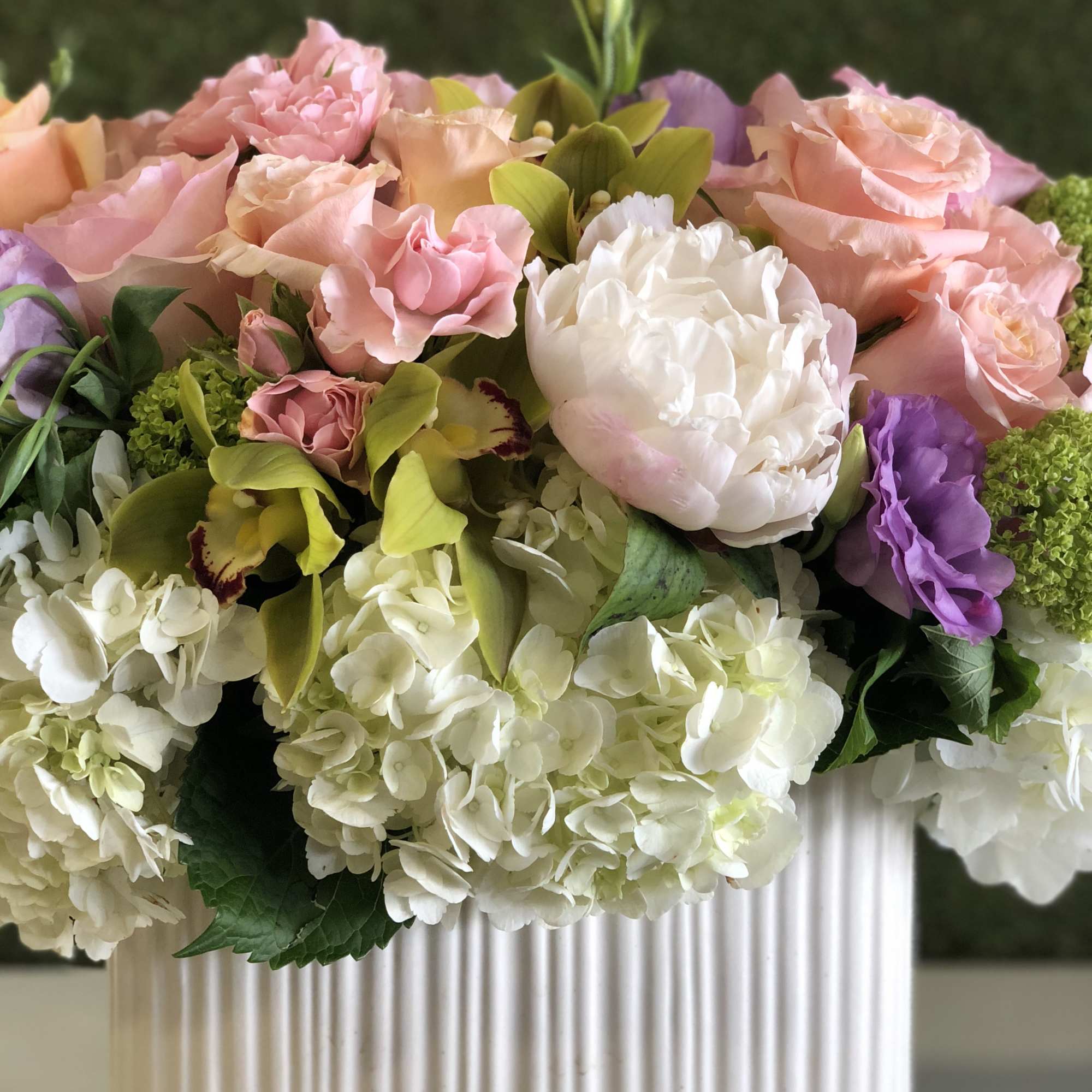 Pink and white floral arrangement in a ribbed white vase