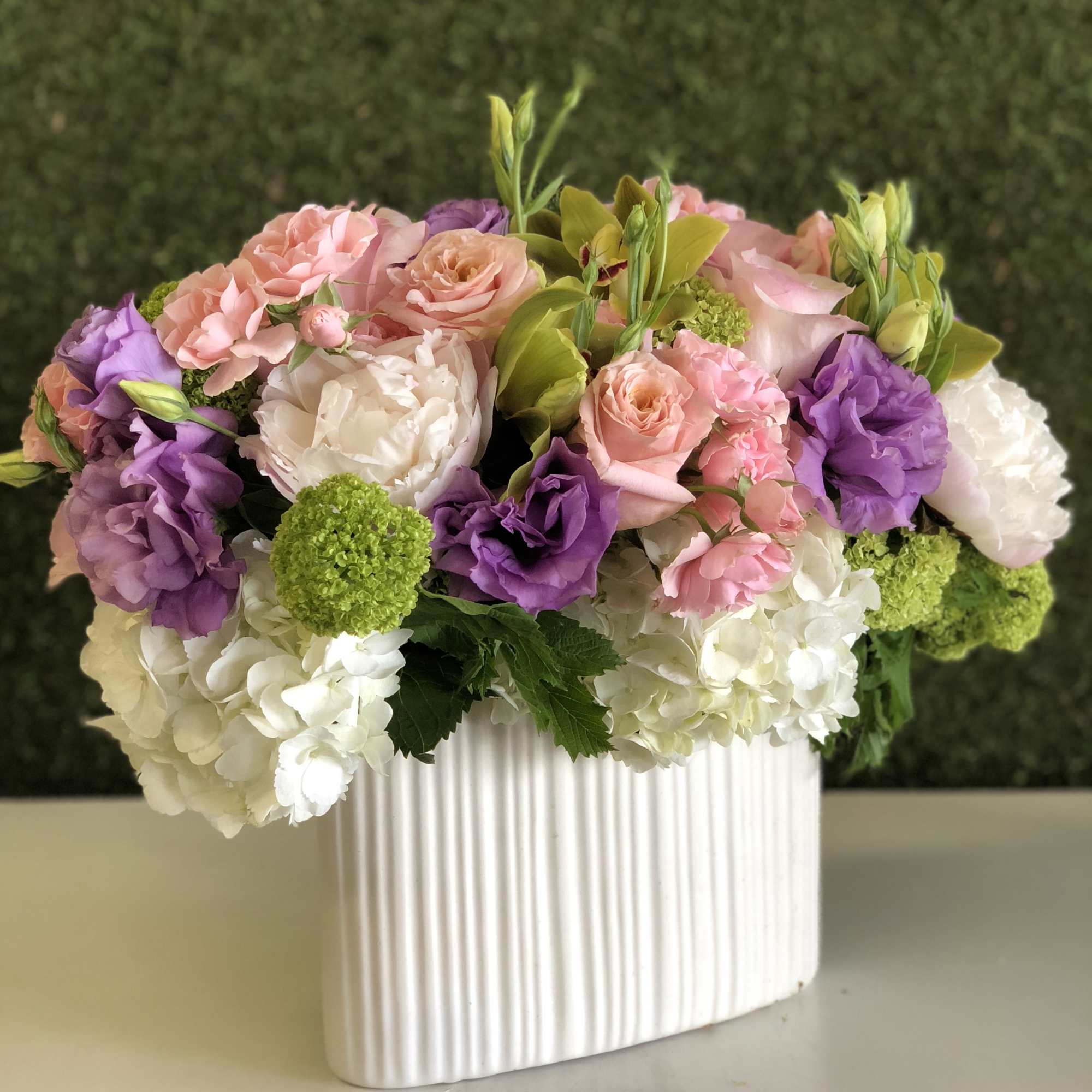 Pink, purple, and white flowers arranged in a ribbed white vase