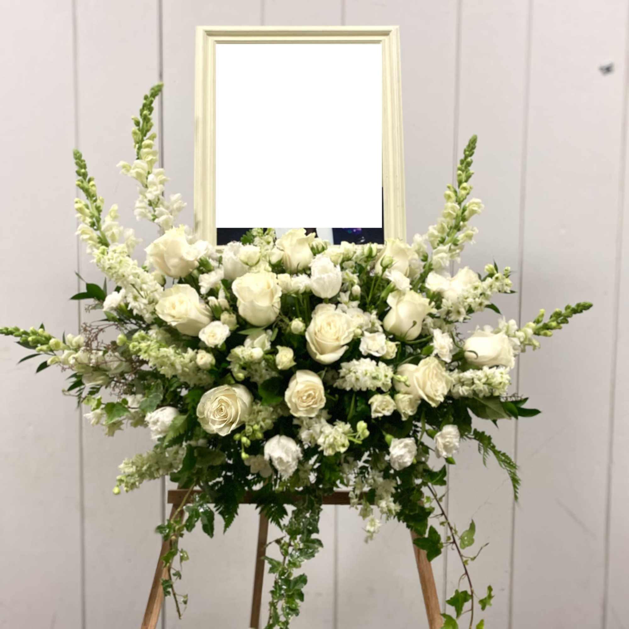 White rose and snapdragon floral arrangement on an easel
