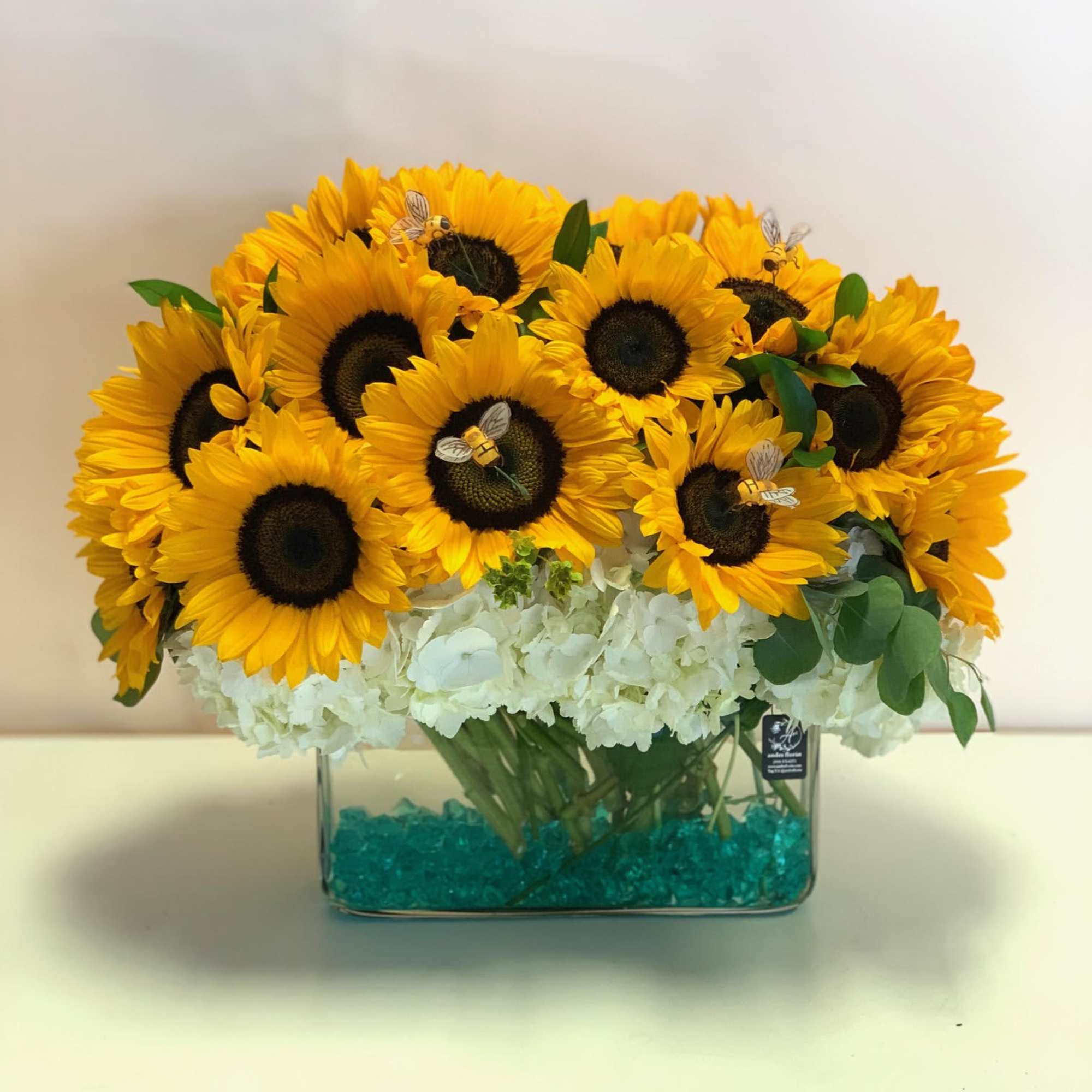 Sunflower arrangement in a clear rectangular vase with white hydrangeas